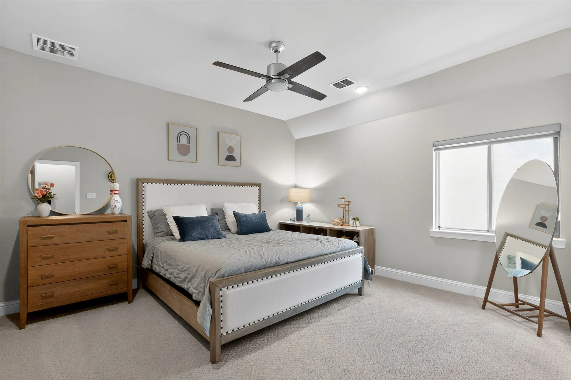 Carpeted bedroom featuring a vaulted ceiling with a ceiling fan, a window, and light gray walls