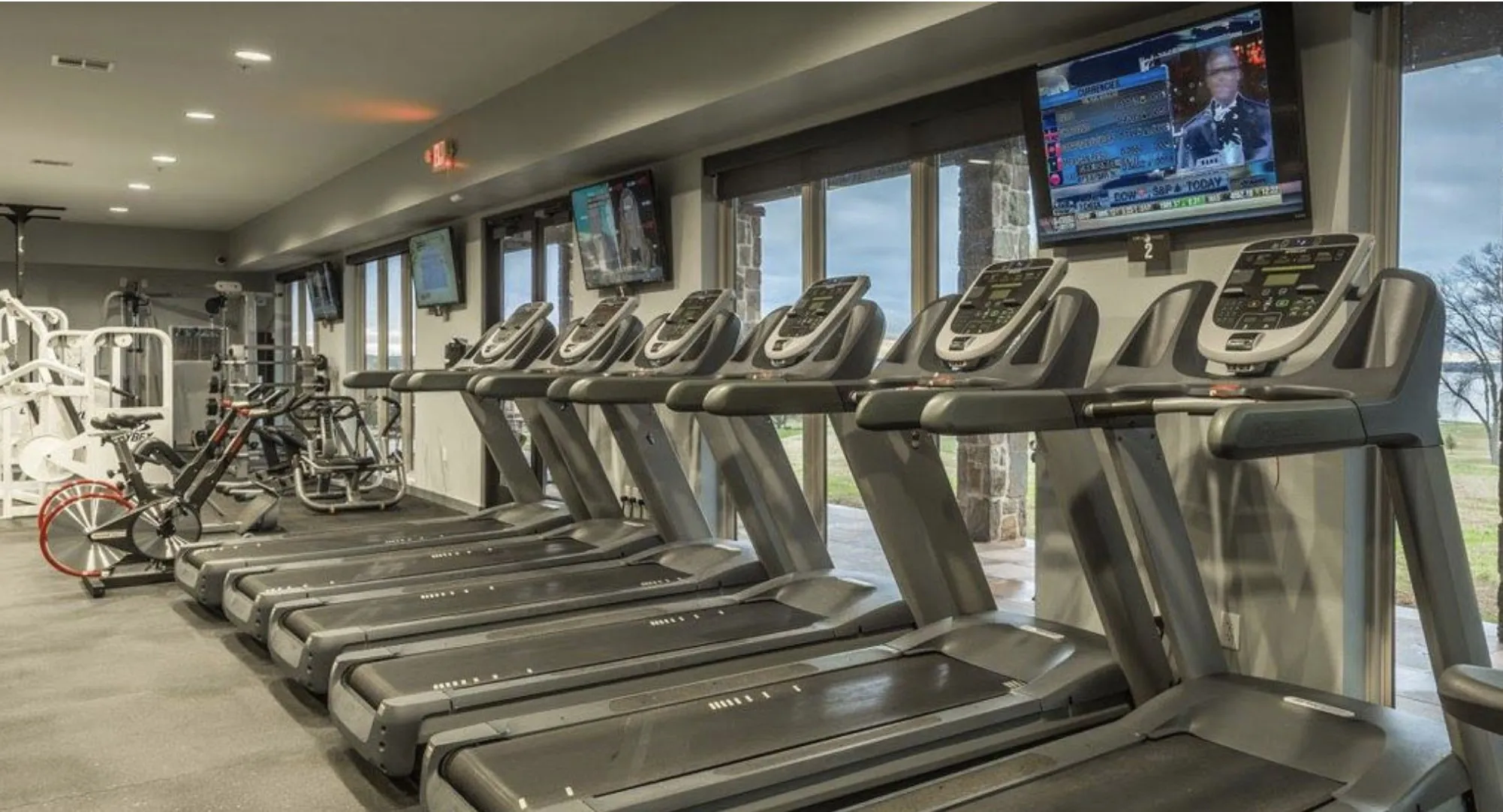 Dedicated fitness center featuring multiple treadmills, exercise bikes, weight machines, and large exterior windows