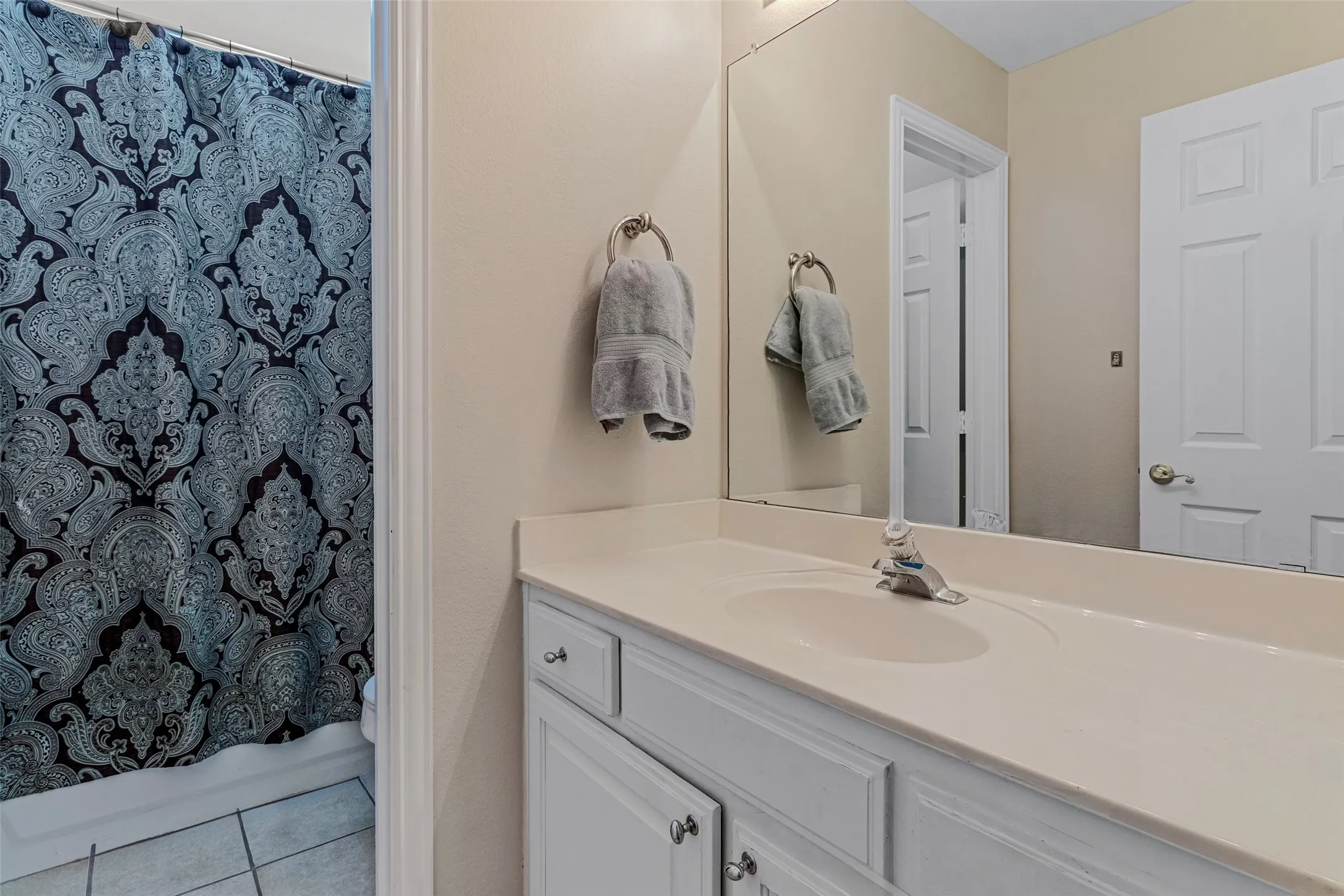 Bathroom vanity featuring white cabinetry, a single sink, and a light-toned countertop
