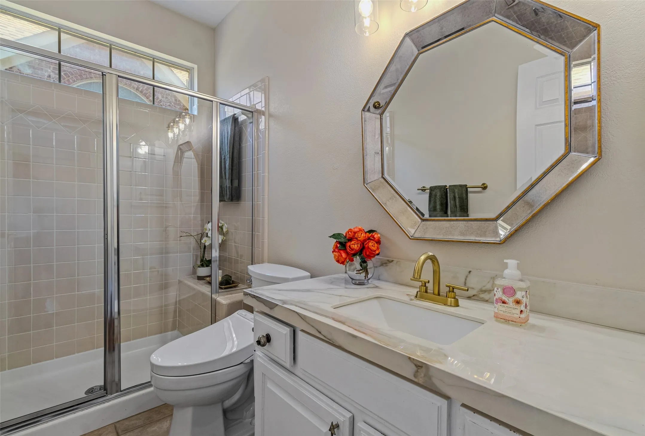Bathroom featuring a glass-enclosed shower with tiled walls and a transom window