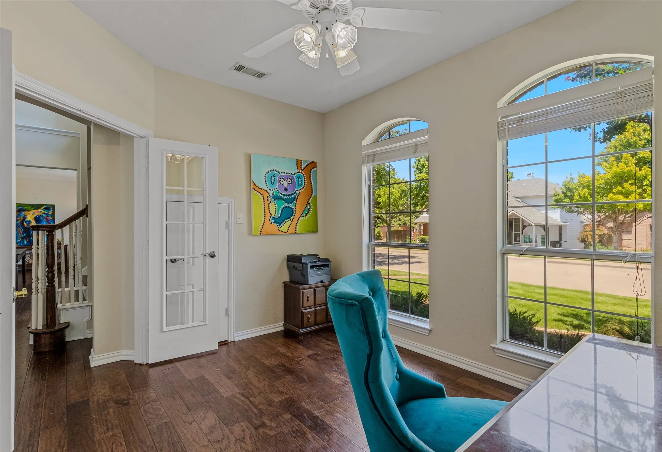 Room featuring wood-finish flooring, a ceiling fan with integrated lighting, and white trim throughout