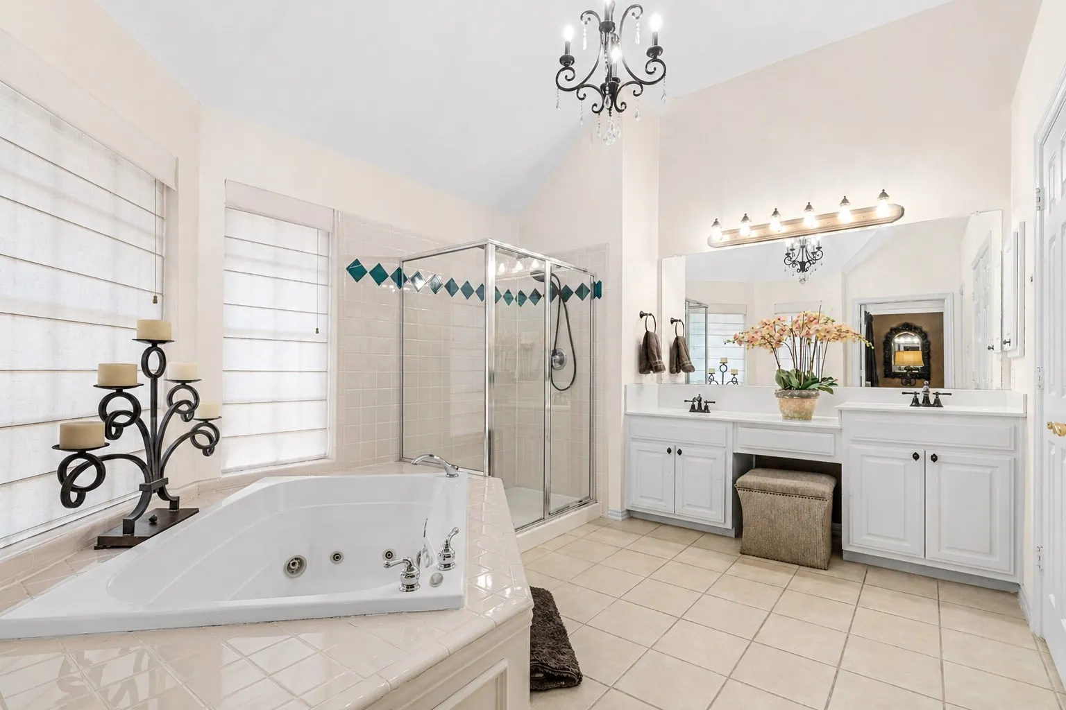 Spacious bathroom featuring a corner soaking tub, glass-enclosed shower, dual vanity with white cabinetry, and ceramic tile flooring