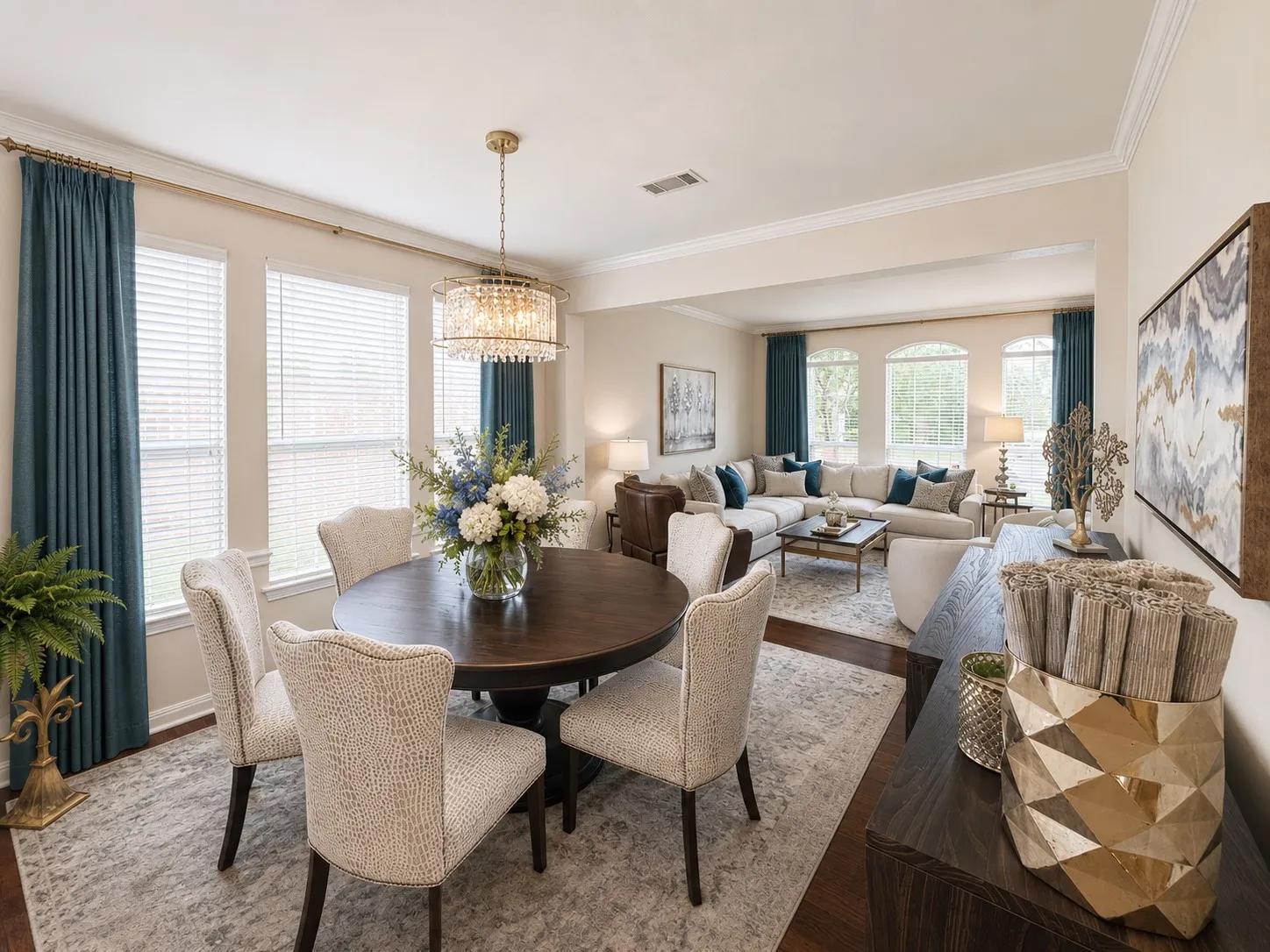 Open-concept living space with crown molding, hardwood-style flooring, and a crystal chandelier