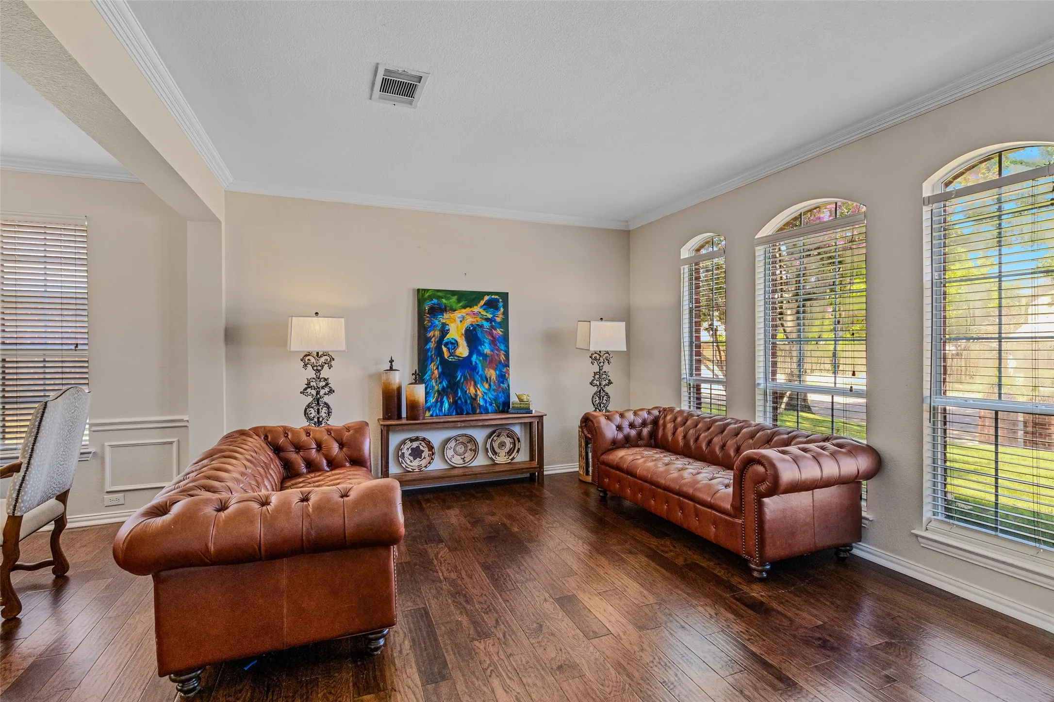 Spacious living area featuring rich wood-finish flooring, elegant crown molding, and wainscoting details