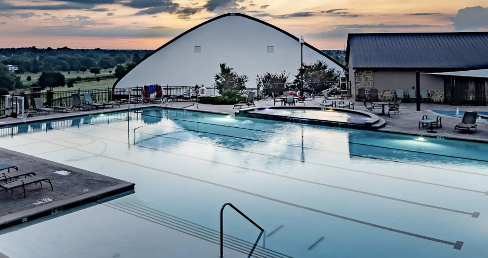 Expansive swimming pool area featuring a large main pool with lane markers, an integrated spa, and a separate smaller pool