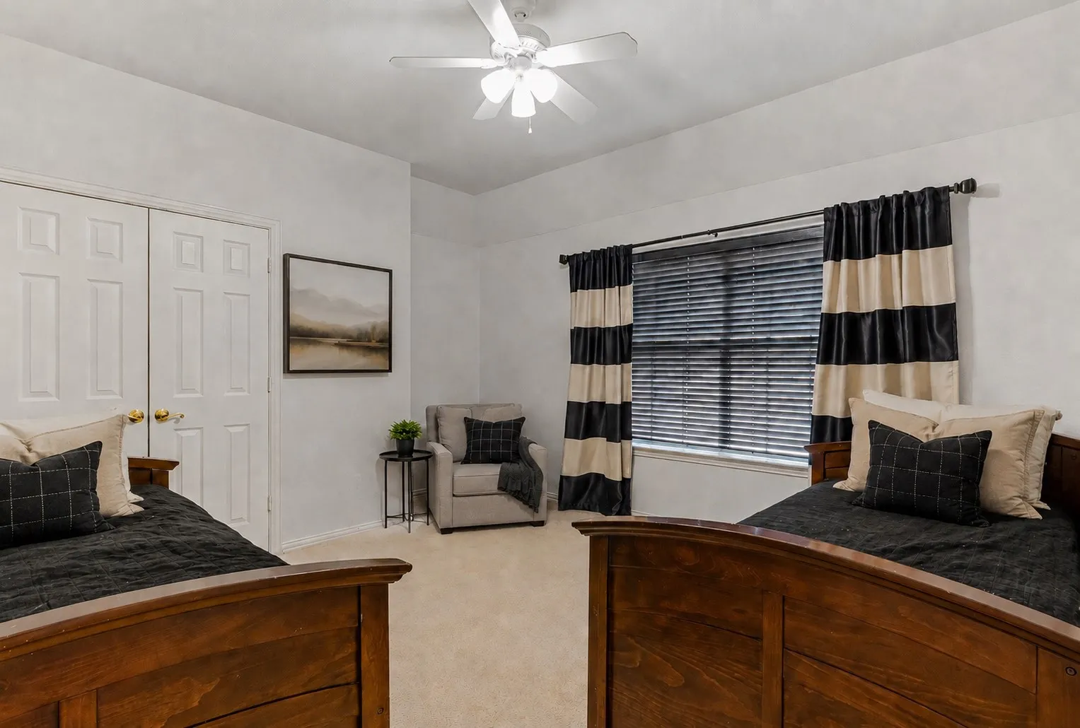 Carpeted room featuring a ceiling fan, window with blinds, and white bi-fold closet doors