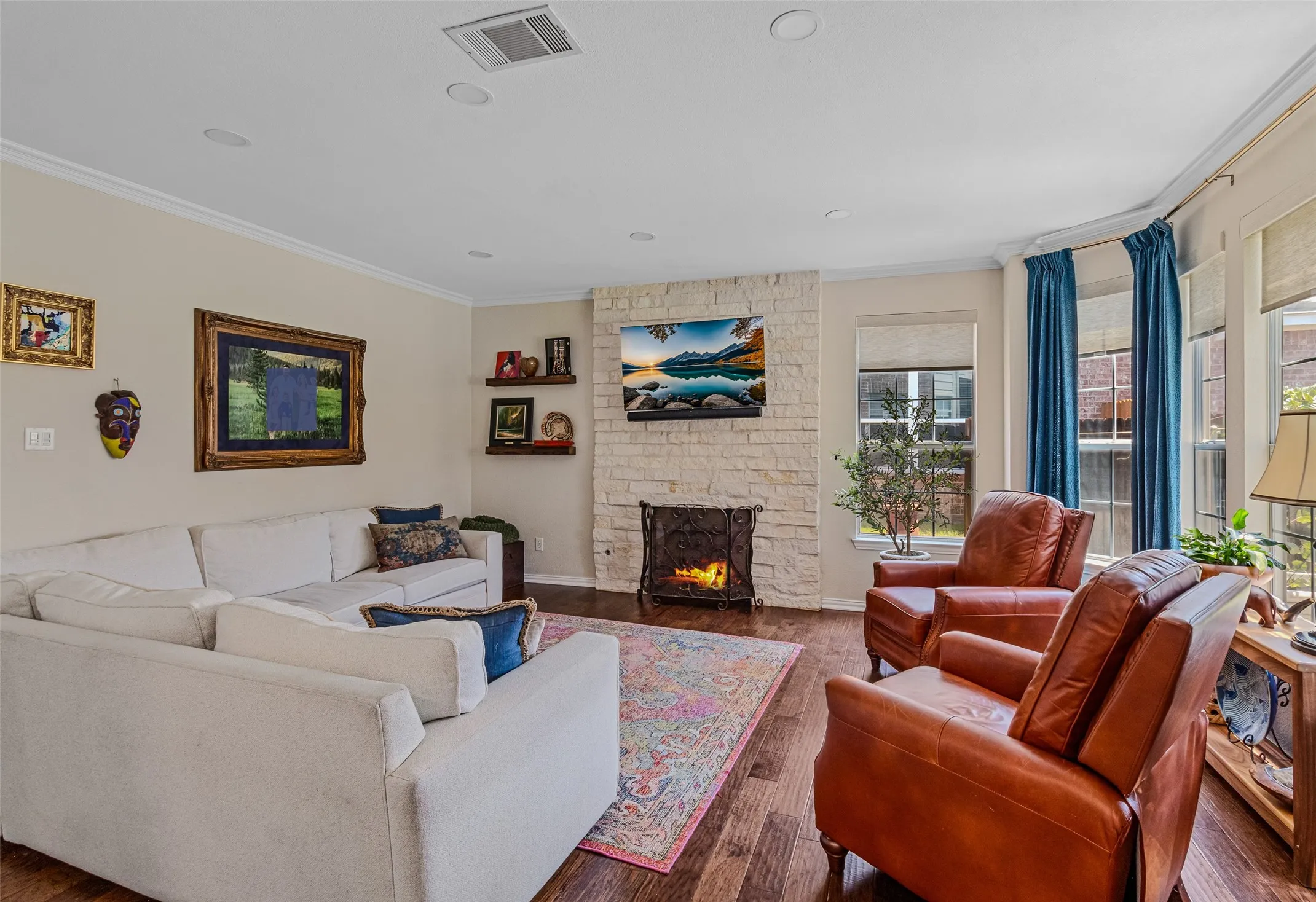 Living area featuring wood-finish flooring, a stone-clad fireplace, recessed lighting, and crown molding