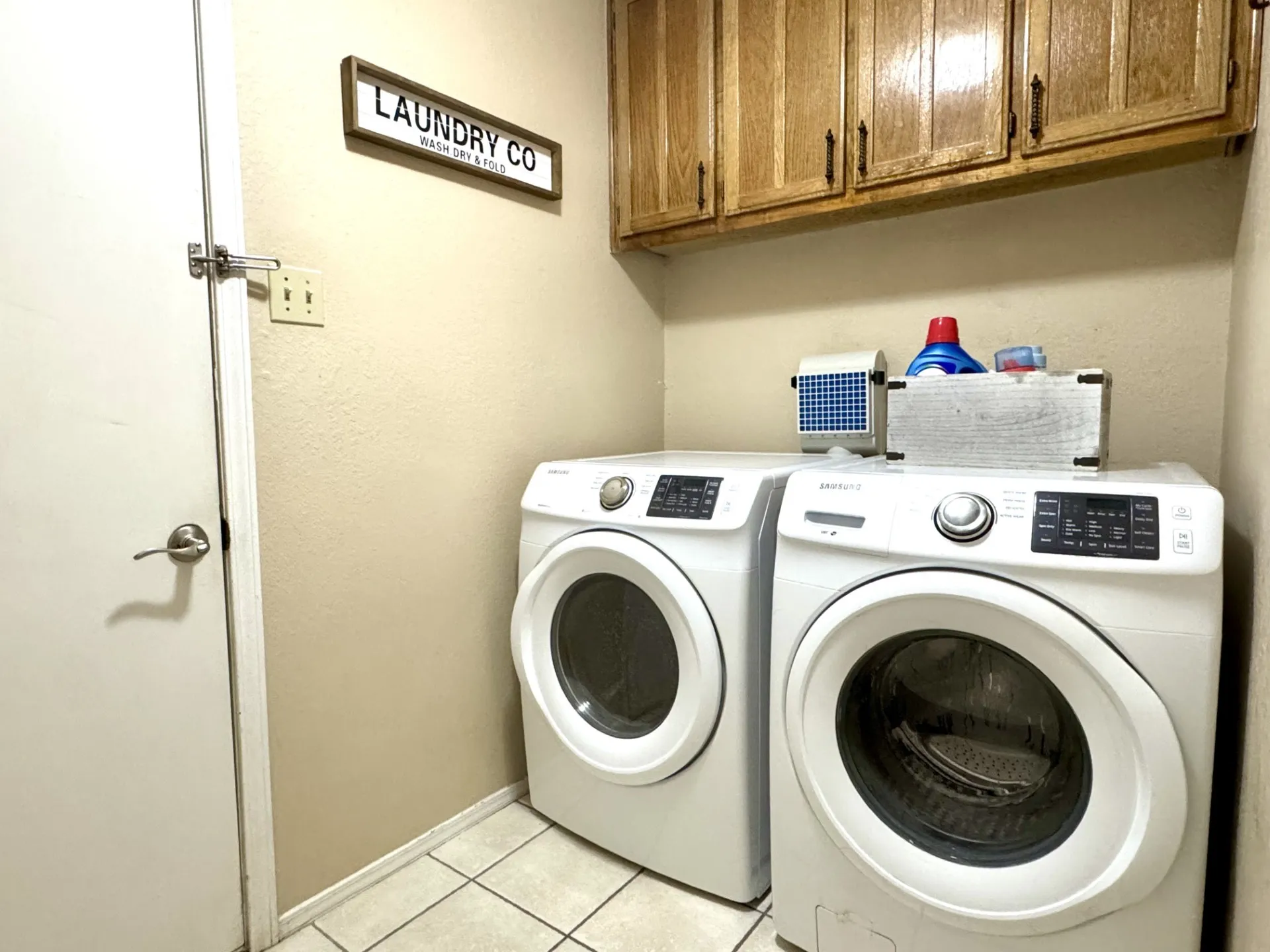 Laundry Room is located by Primary Bedroom: featuring tiled flooring and wood-finish cabinetry... Additional similar cabinetry located nearby for linens (not shown).