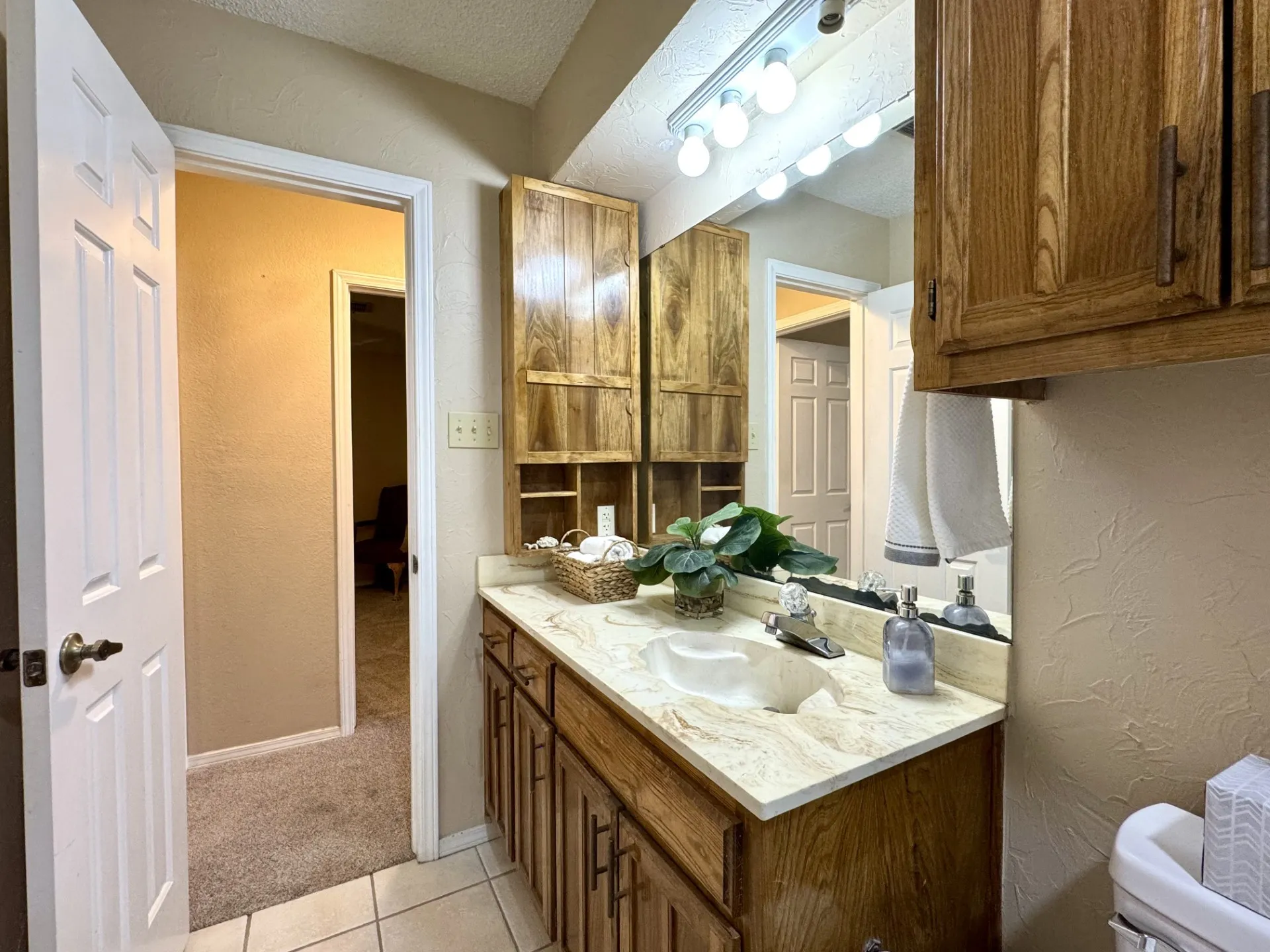 Full HALL Bath is located near the 2 bedrooms: featuring a marble-like countertop with integrated sink, and wood cabinetry