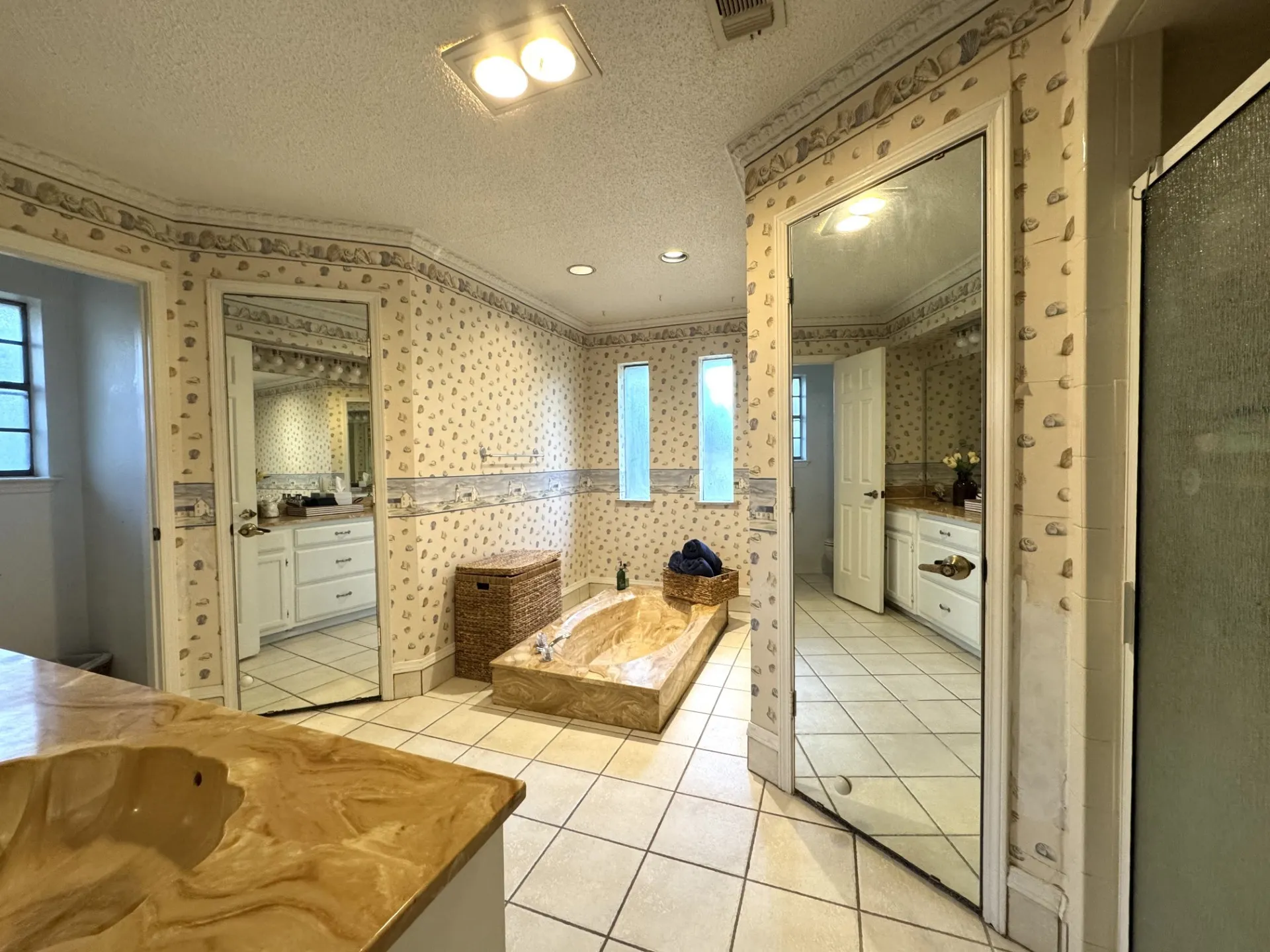 Spacious Primary Bathroom features a SUNKEN Tub, DUAL Walk-In Closets with Dressing Mirrors, tiled flooring, and multiple windows