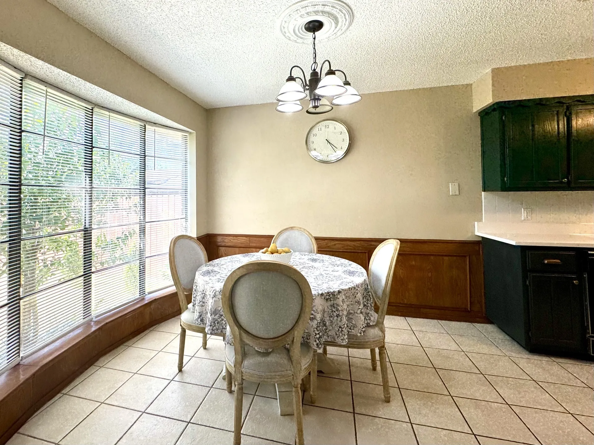Bay window dining area featuring tile flooring, wood paneling, a ceiling medallion with a chandelier, and a built-in counter with cabinetry and a white subway tile backsplash