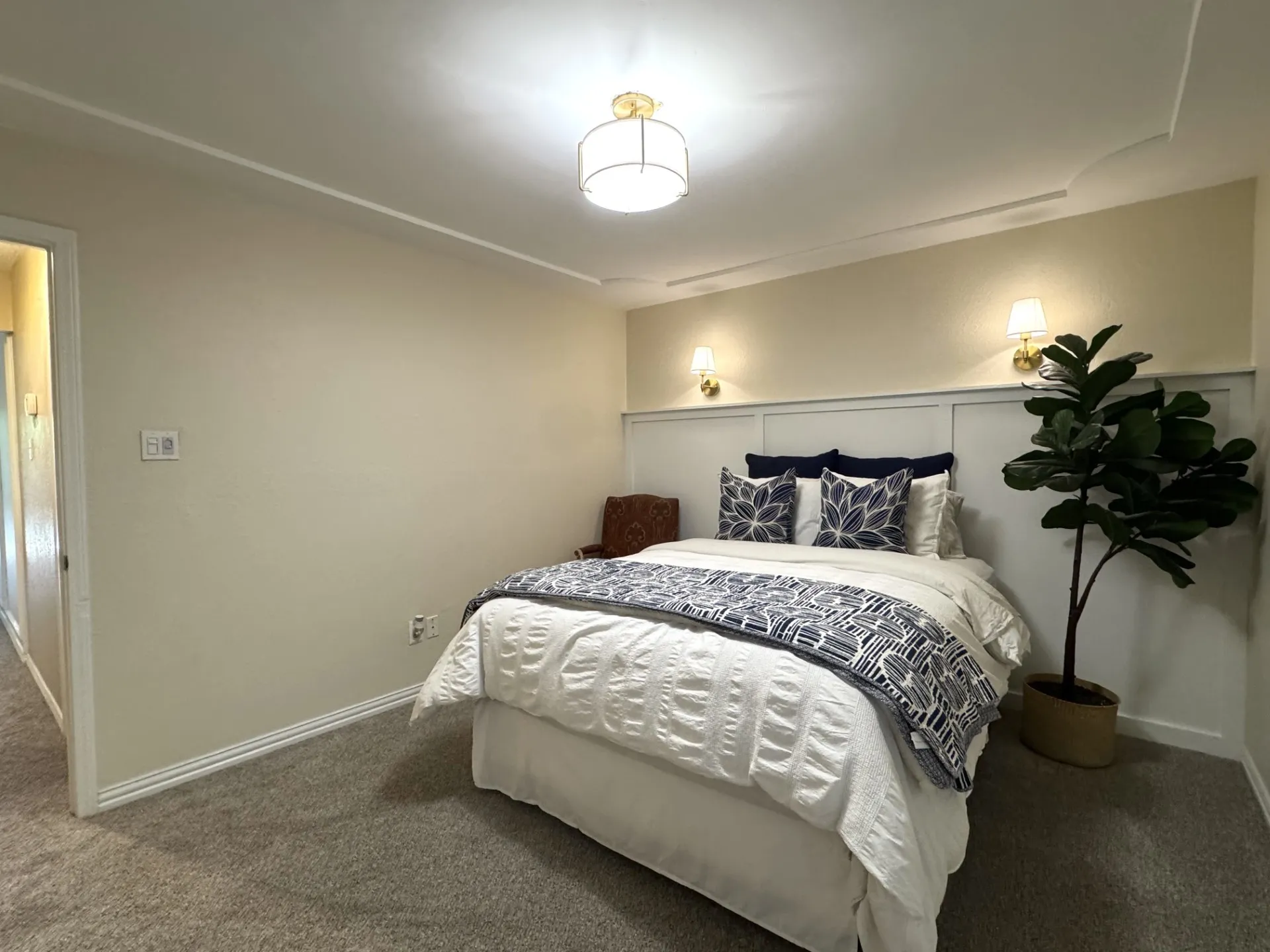 Bedroom 2 features carpeting, a decorative wainscoting accent wall with two mounted sconces, a ceiling light fixture, and crown molding