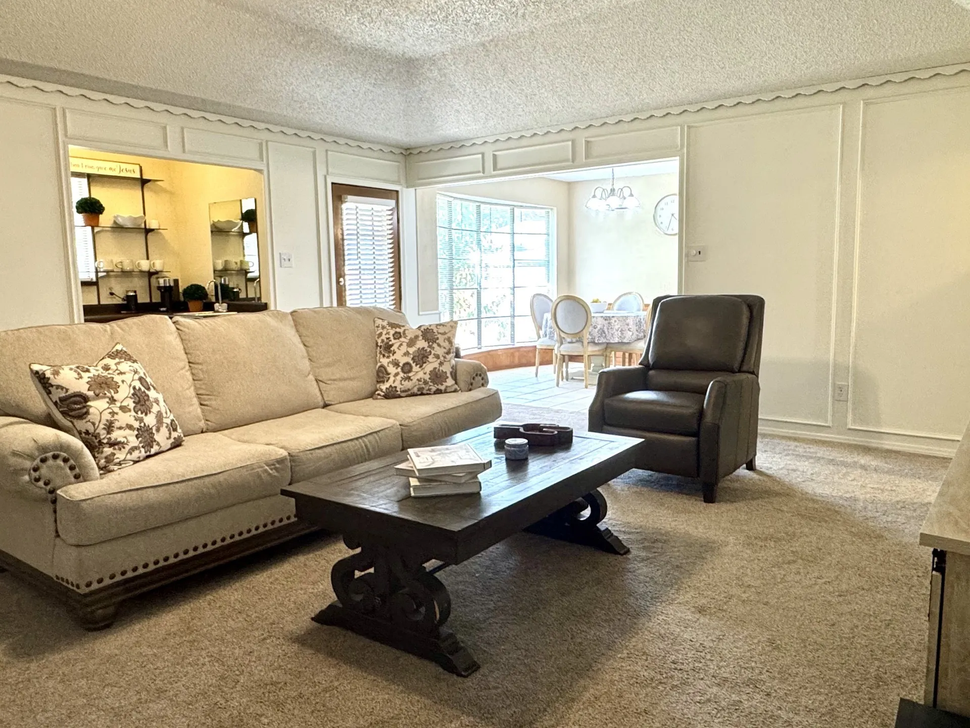 Carpeted living area OPENS to Dining and Kitchen... featuring wainscoting with decorative trim, an open doorway, and a built-in Wet Bar.