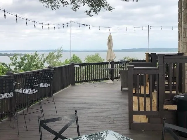 Expansive outdoor deck with dark wood-finish railing, overlooking a large body of water