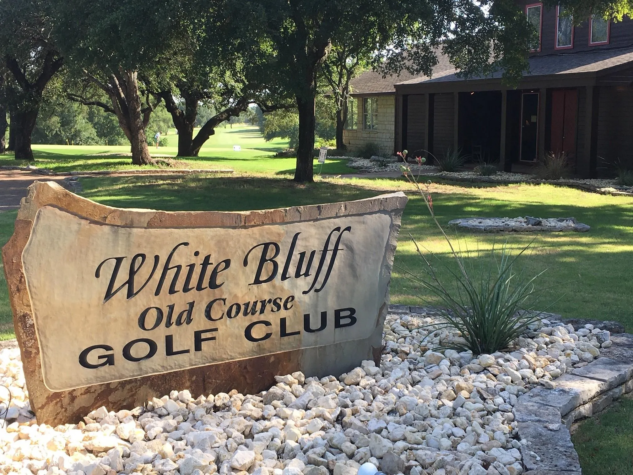 Stone monument signage with integrated landscaping featuring white gravel and a decorative plant