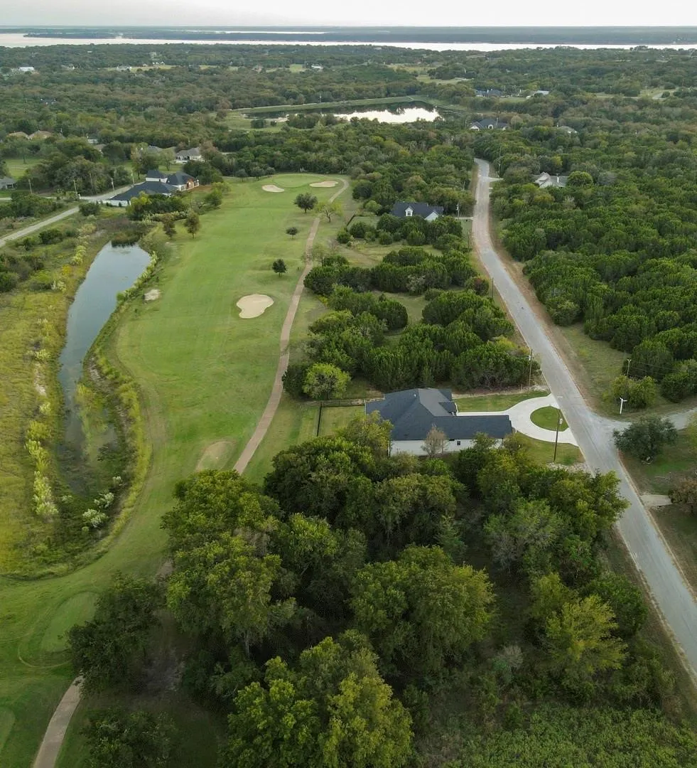 Aerial perspective showcasing a single-story residence with a dark roof and a circular drive
