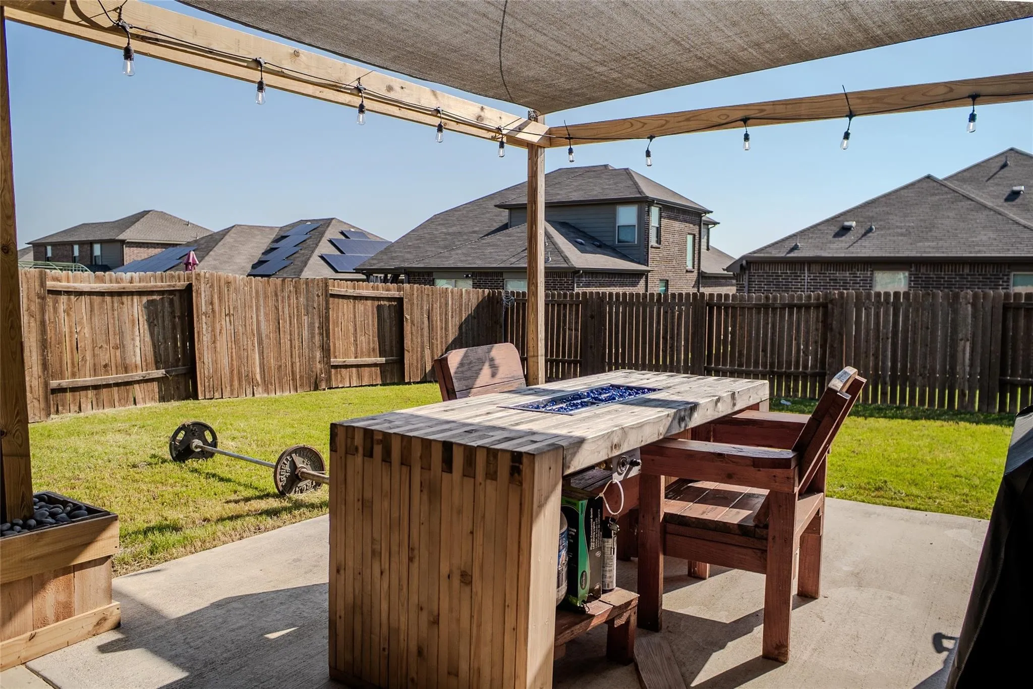 Expansive concrete patio featuring a shade canopy with string lighting
