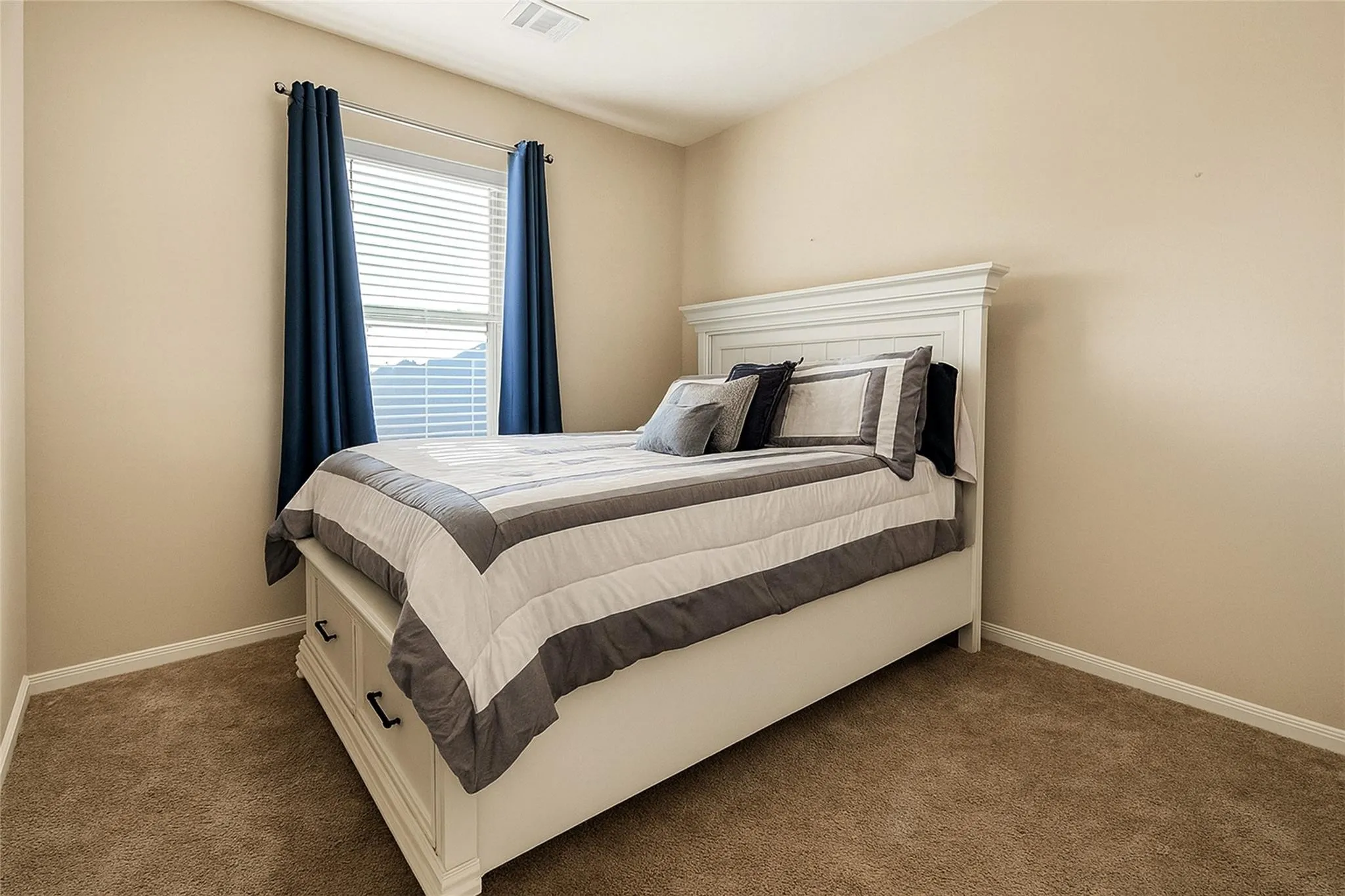 Bedroom featuring neutral wall paint, carpet flooring, a window with horizontal blinds, and a ceiling vent