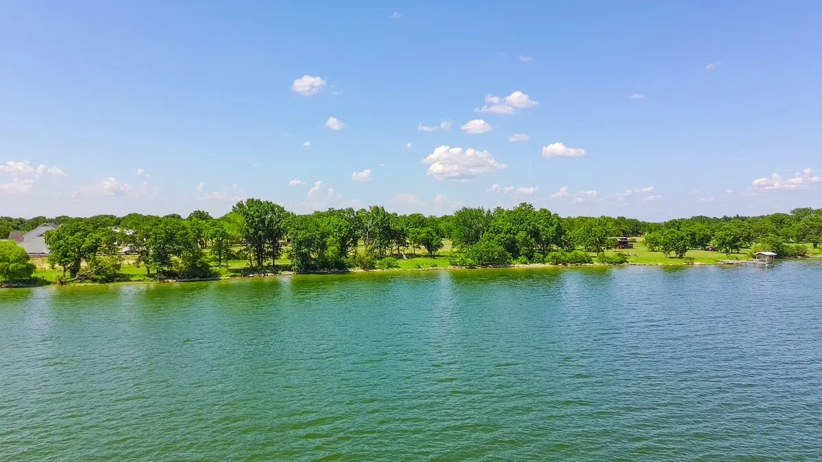 Waterfront property featuring a private boat dock, lush green trees, and expansive water frontage