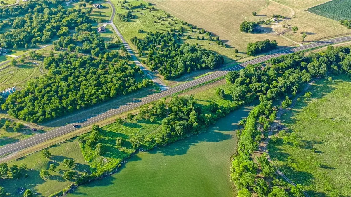 Expansive parcel featuring mature tree coverage, open fields, and frontage on a water body