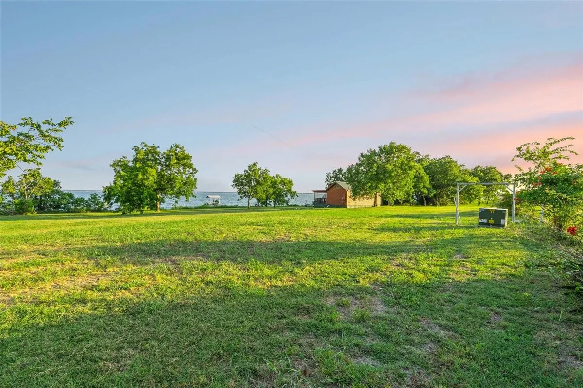 Expansive grassy lawn with mature trees and waterfront access