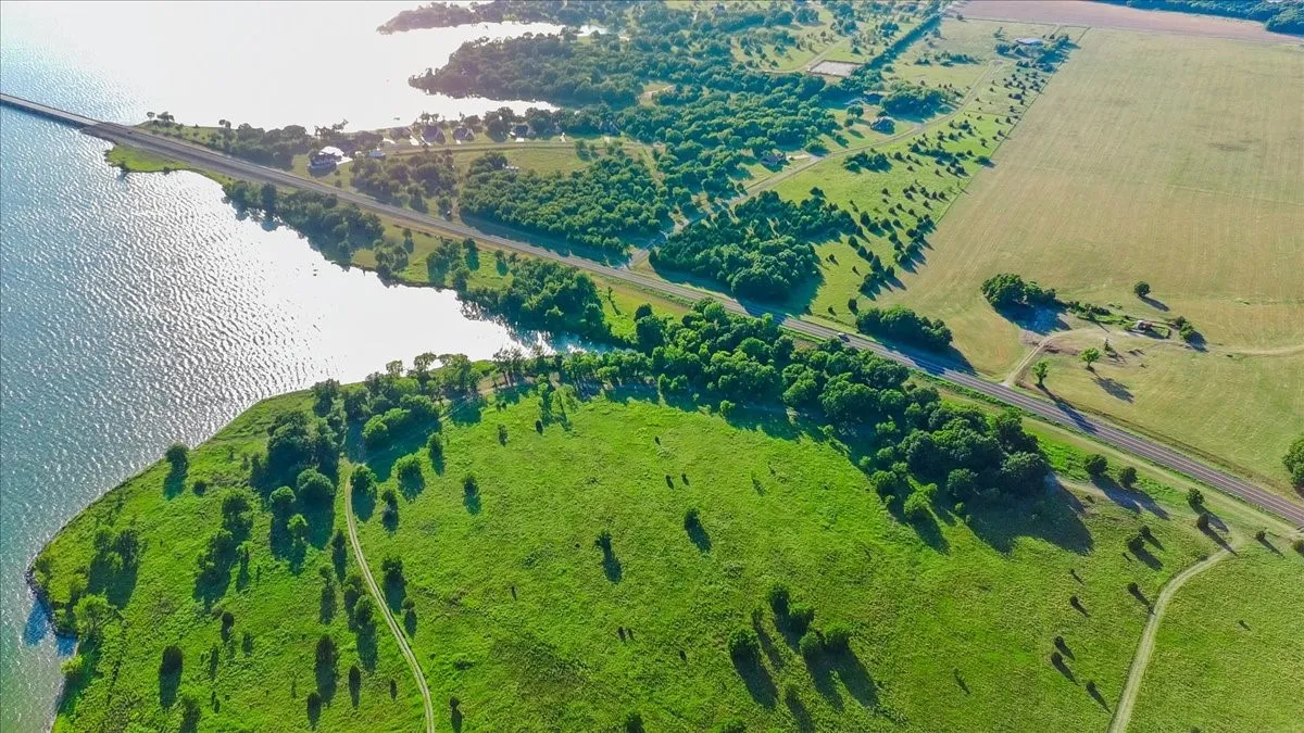 Expansive waterfront property featuring a substantial land parcel, direct water frontage, a paved road, and abundant green space