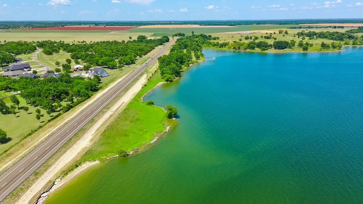 Expansive waterfront property featuring a large lake, verdant shoreline, and mature trees