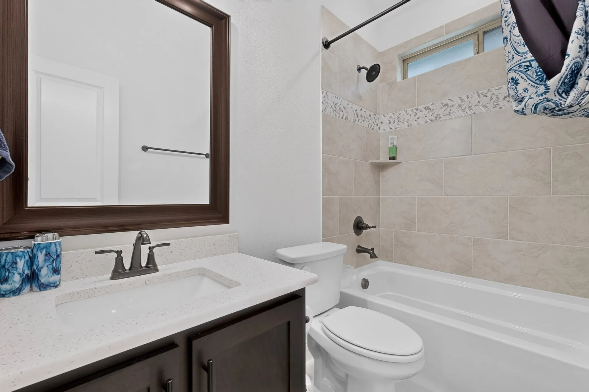 Bathroom vanity with a dark wood-finish frame mirror and a white speckled countertop