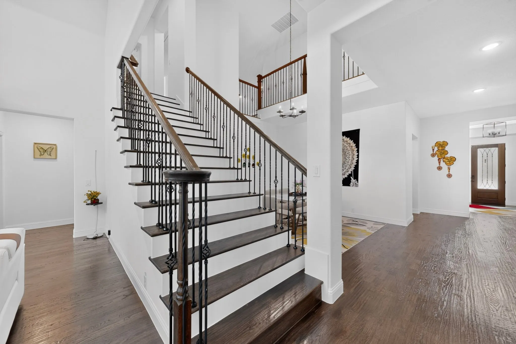 Grand staircase featuring dark wood-finish treads and risers, intricate wrought iron balusters, and a rich wood-finish handrail