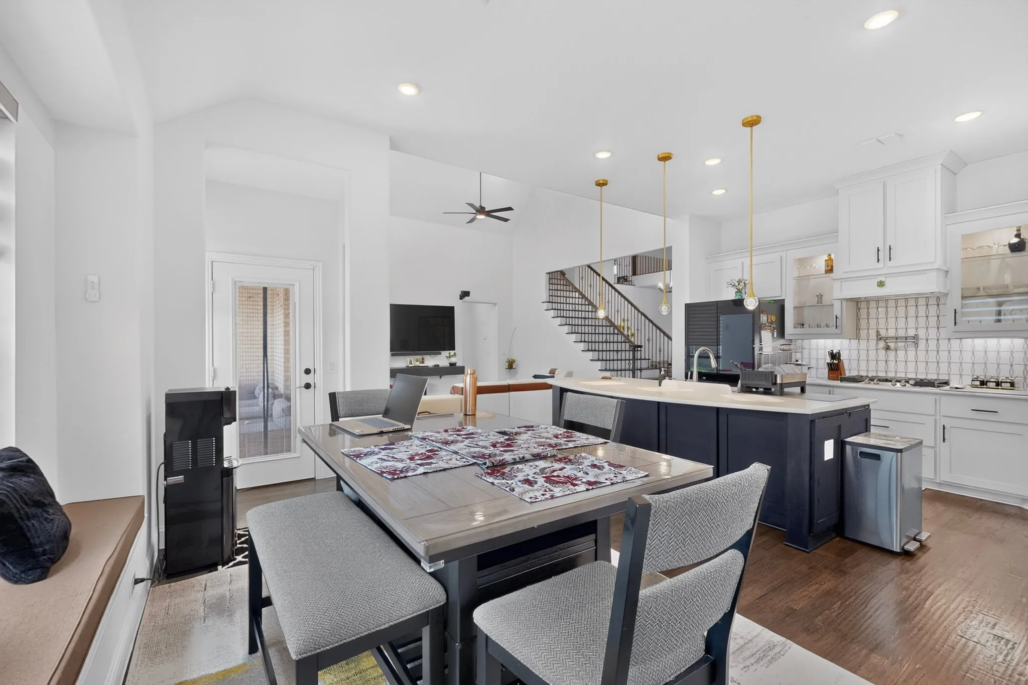 Open-concept kitchen featuring an oversized island with seating, white shaker cabinetry, and a tile backsplash