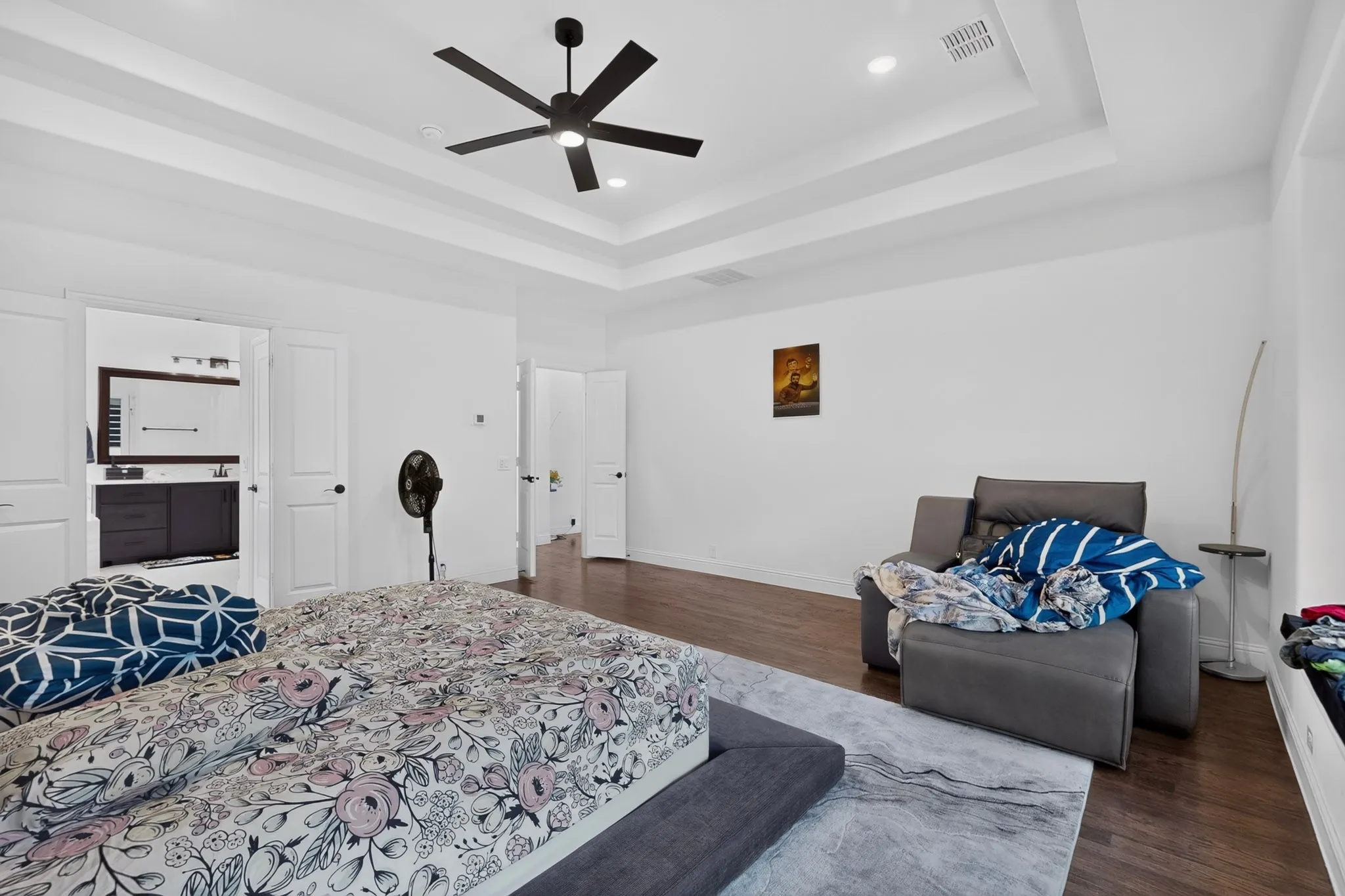 Spacious room featuring a tray ceiling with a ceiling fan, recessed lighting, and wood-finish flooring