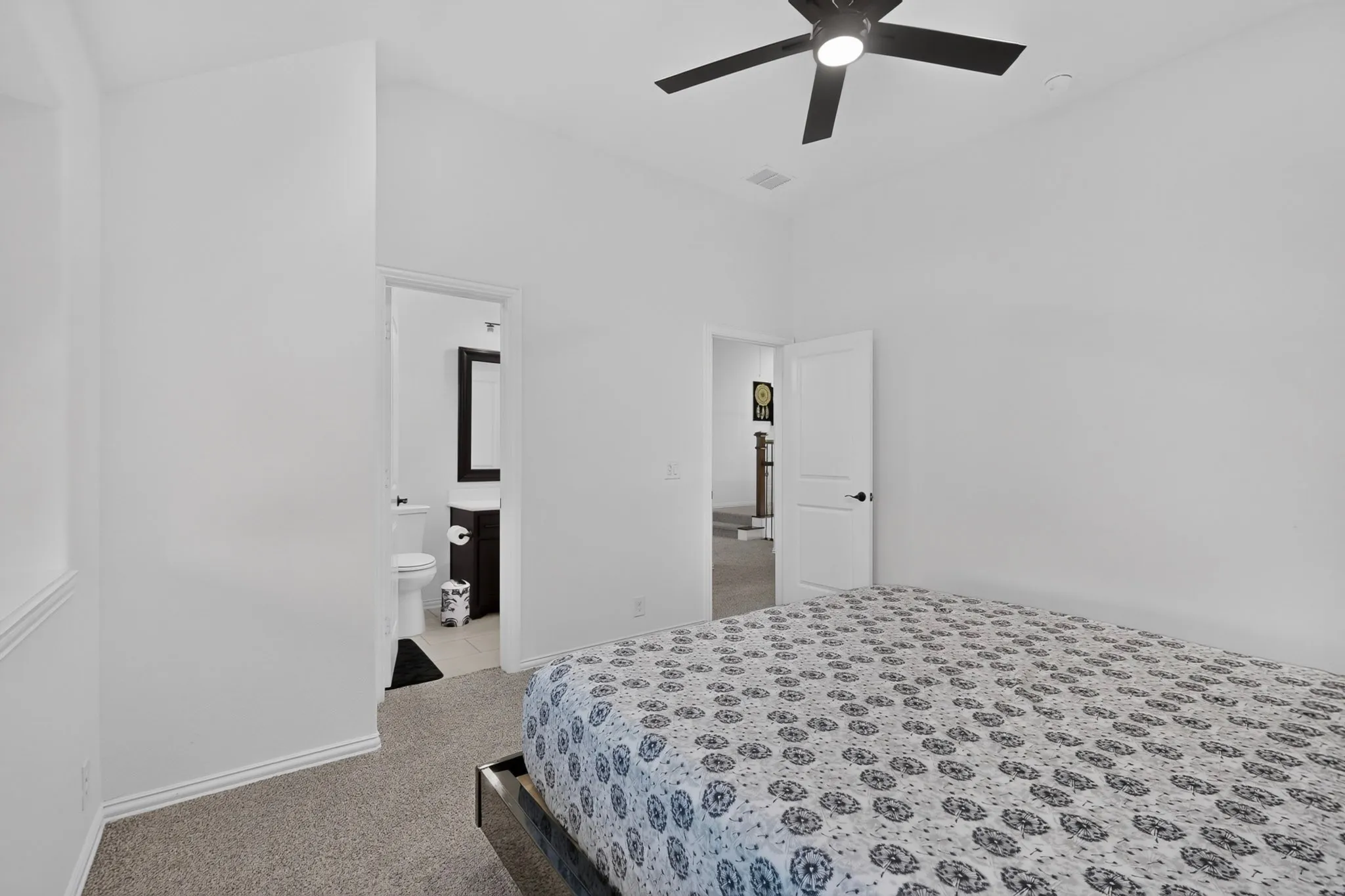Carpeted room with vaulted ceilings and a black ceiling fan