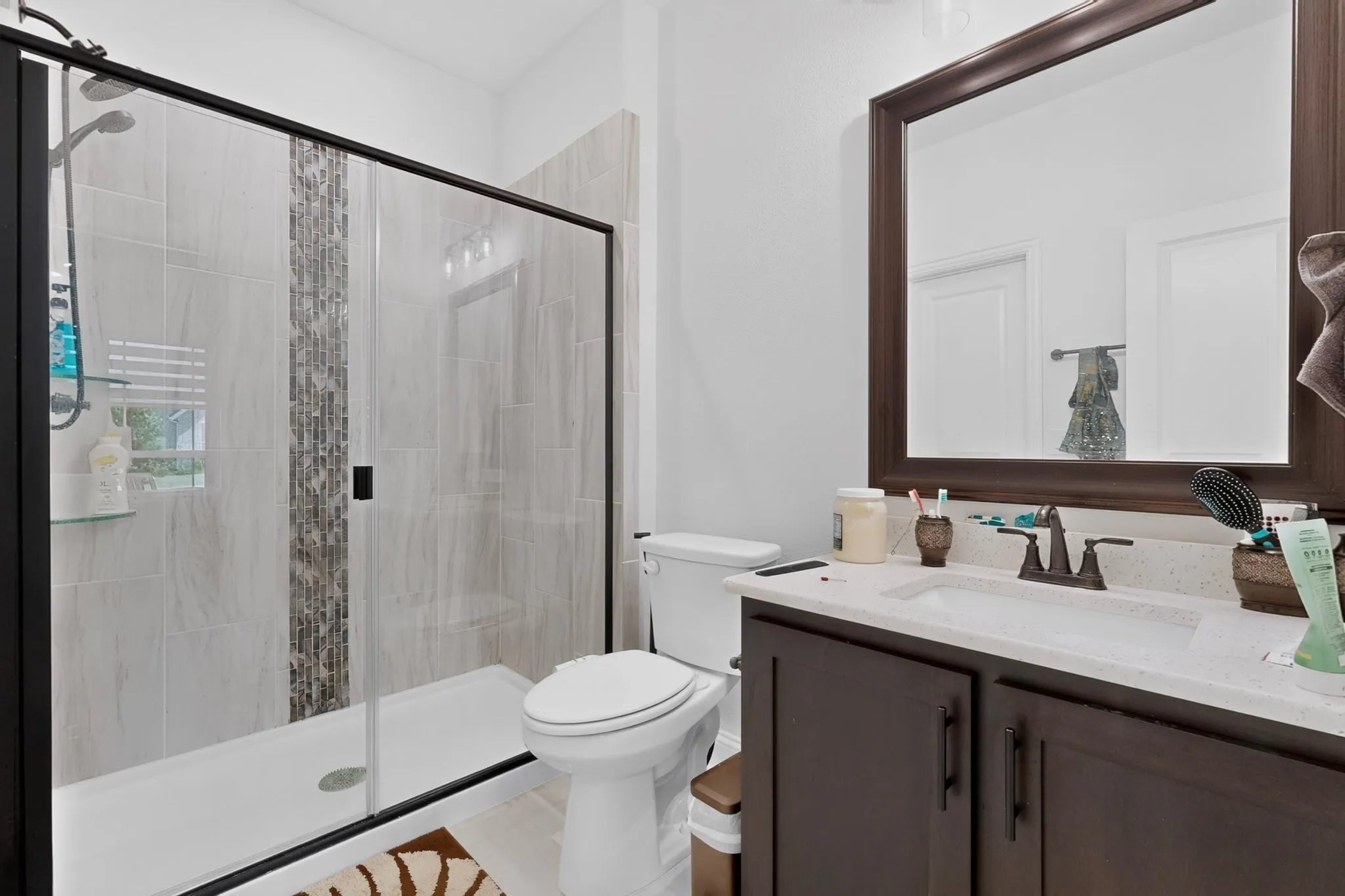 Bathroom featuring a glass-enclosed shower with tiled walls and a decorative mosaic accent