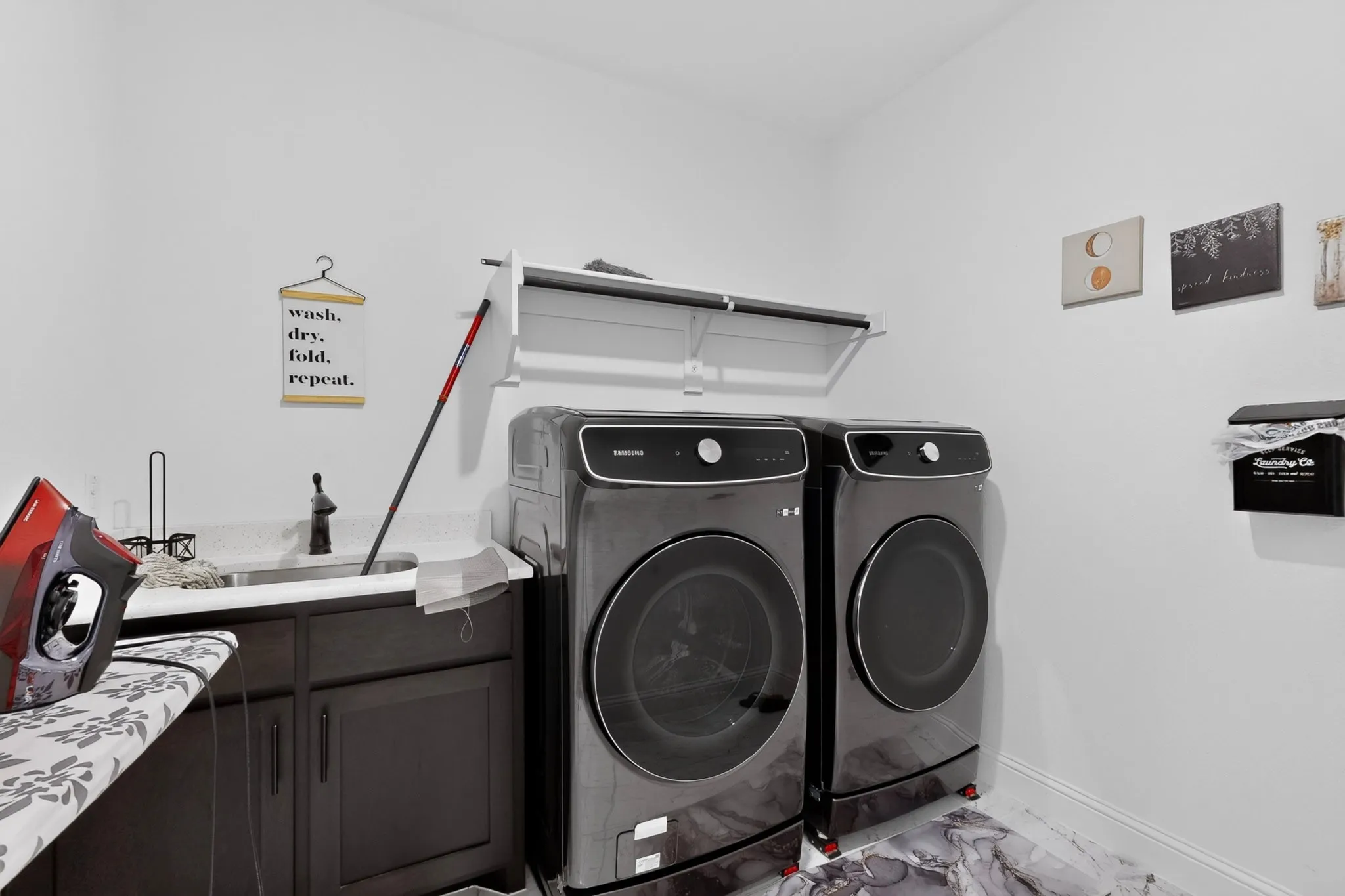 Laundry room featuring a utility sink with a black faucet, built-in cabinetry, and white wall shelving
