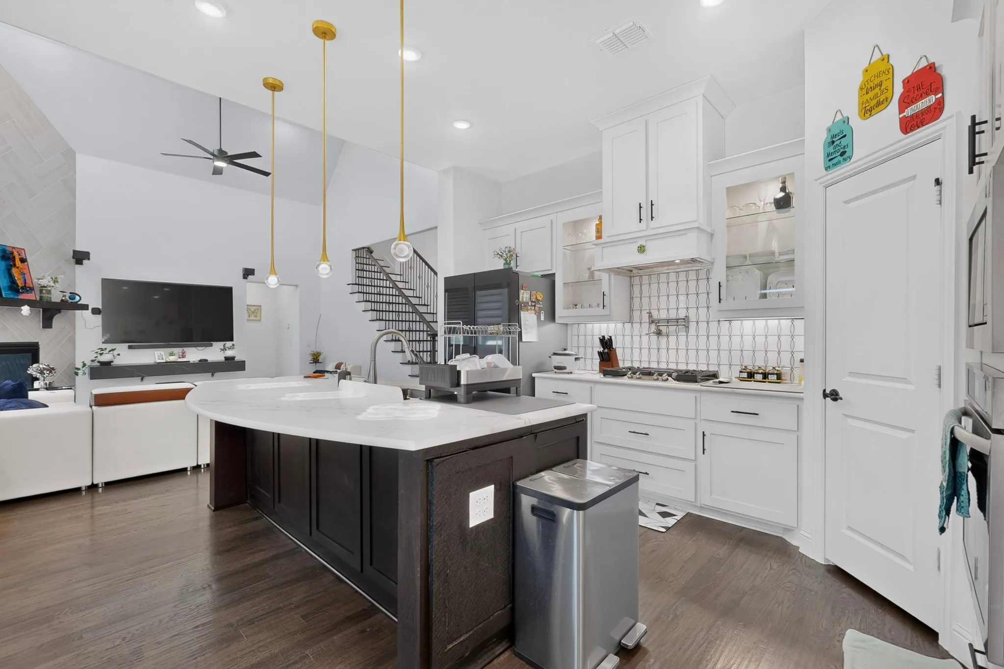 Open-concept kitchen featuring a dark wood island with light countertops, white cabinetry, a subway tile backsplash, and dark wood-finish flooring