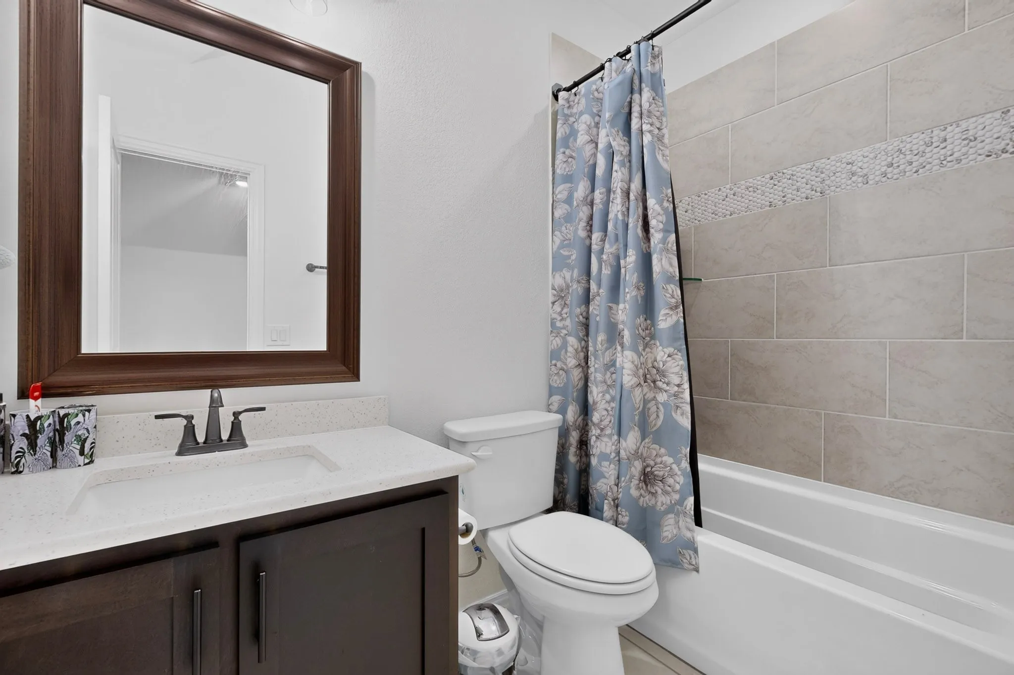 Bathroom featuring a dark wood-finish vanity with a light countertop, a white under-mount sink, and dark bronze fixtures