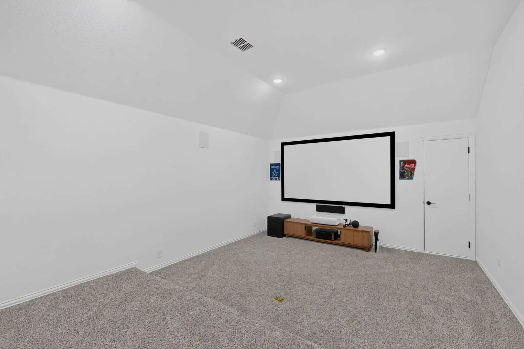Dedicated media room featuring a large projection screen, wall-mounted speakers, and recessed lighting