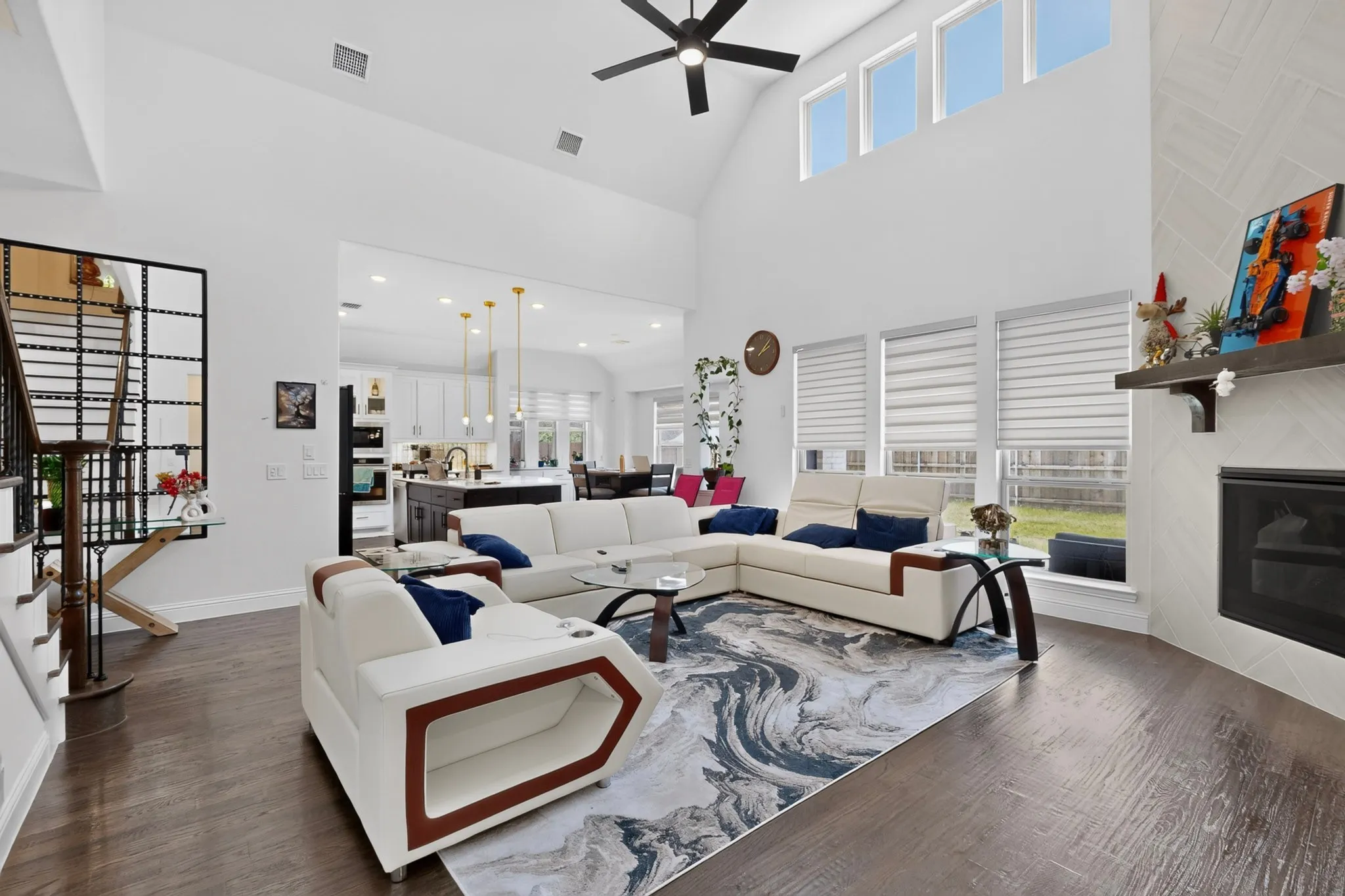 Two-story living area with dark wood-finish flooring, a vaulted ceiling, and a black ceiling fan