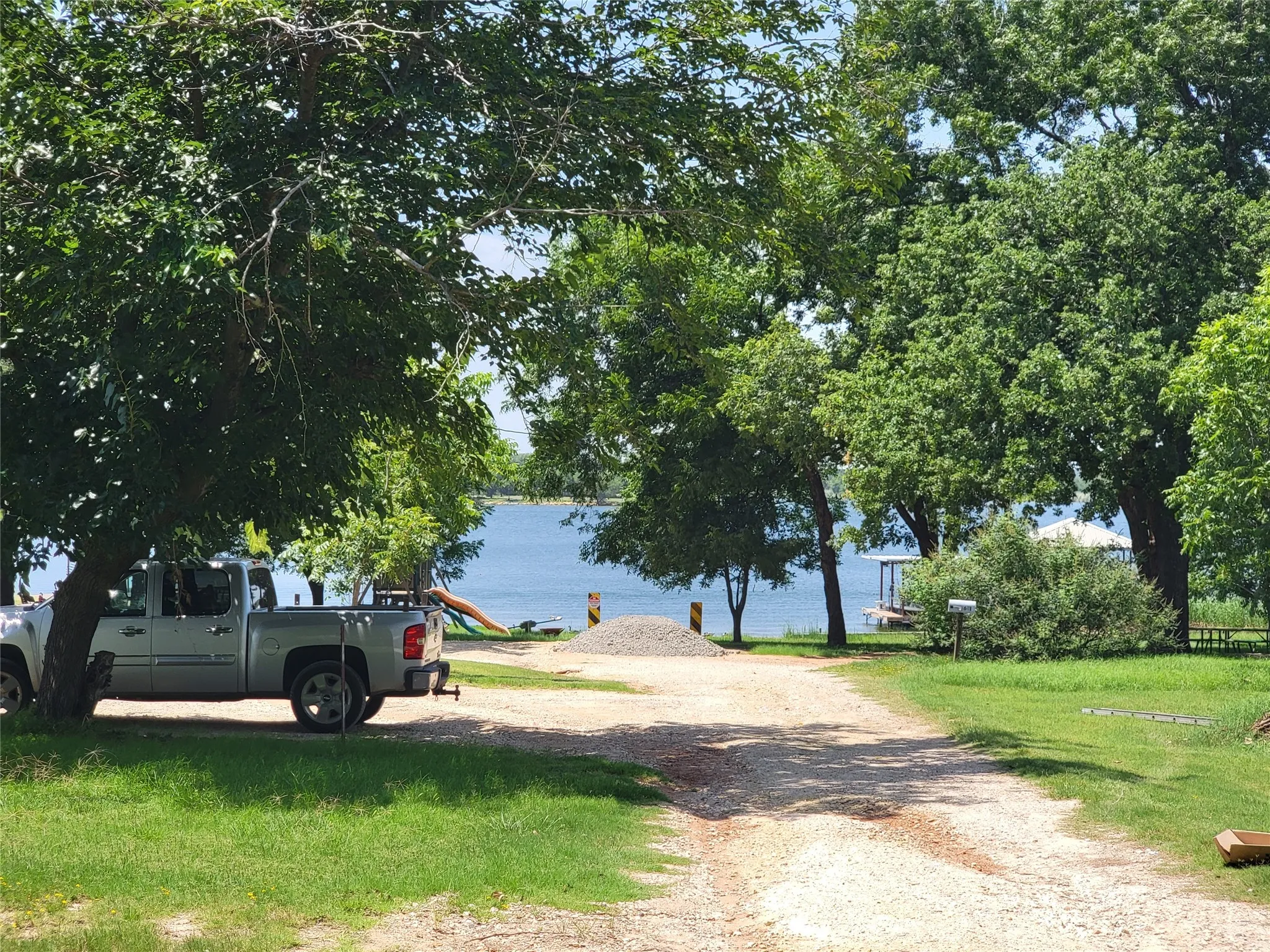 Gravel drive with mature trees and a waterfront setting