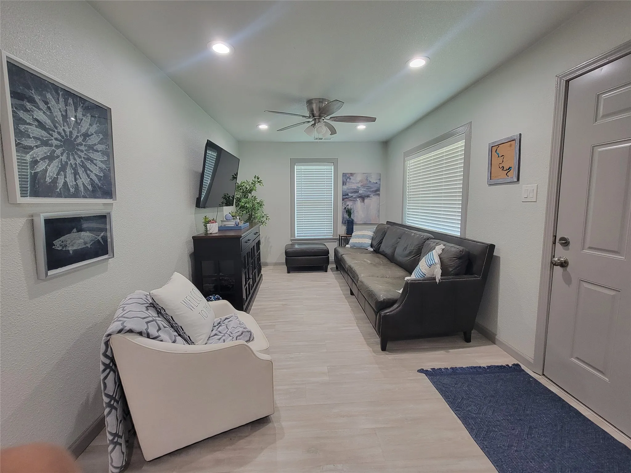 Spacious living area featuring light wood-finish flooring, recessed lighting, and a ceiling fan