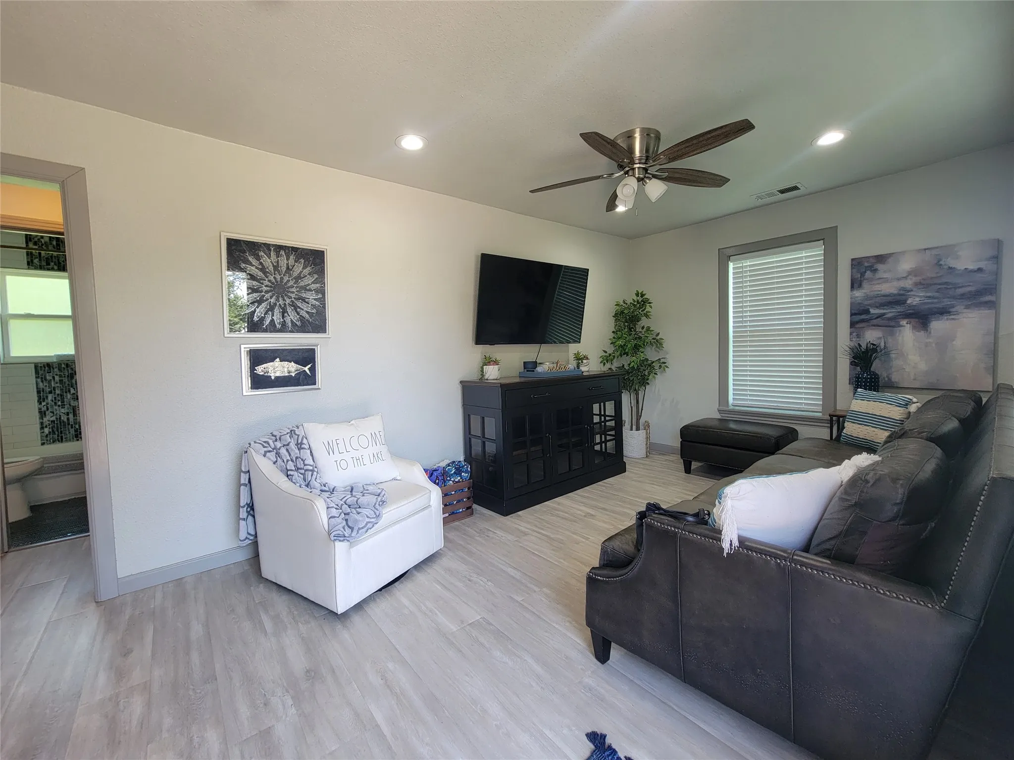 Living area featuring light wood-finish flooring, recessed lighting, and a ceiling fan with integrated light fixture