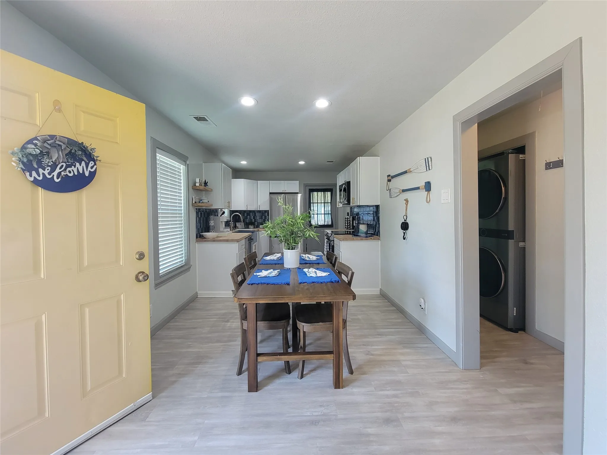 Bright entry leading to an open-concept living space with light wood-finish flooring