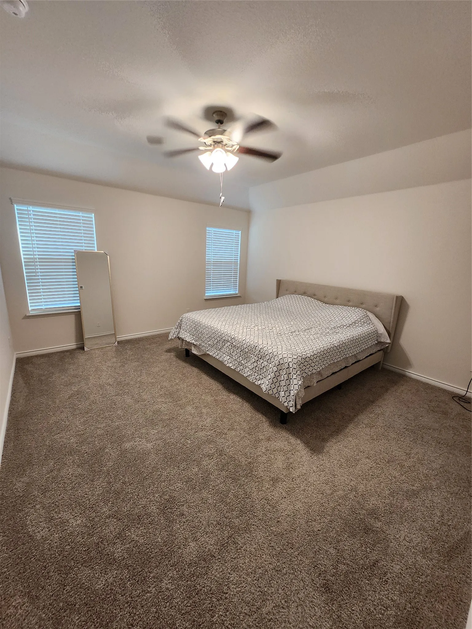 Spacious room featuring neutral carpeting, a ceiling fan with integrated lighting, and white walls