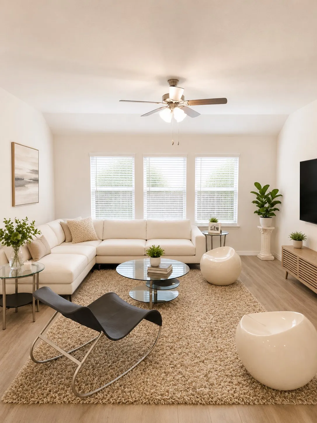 Vaulted ceiling living area featuring a ceiling fan with light kit, three large windows with blinds, and wood-finish flooring