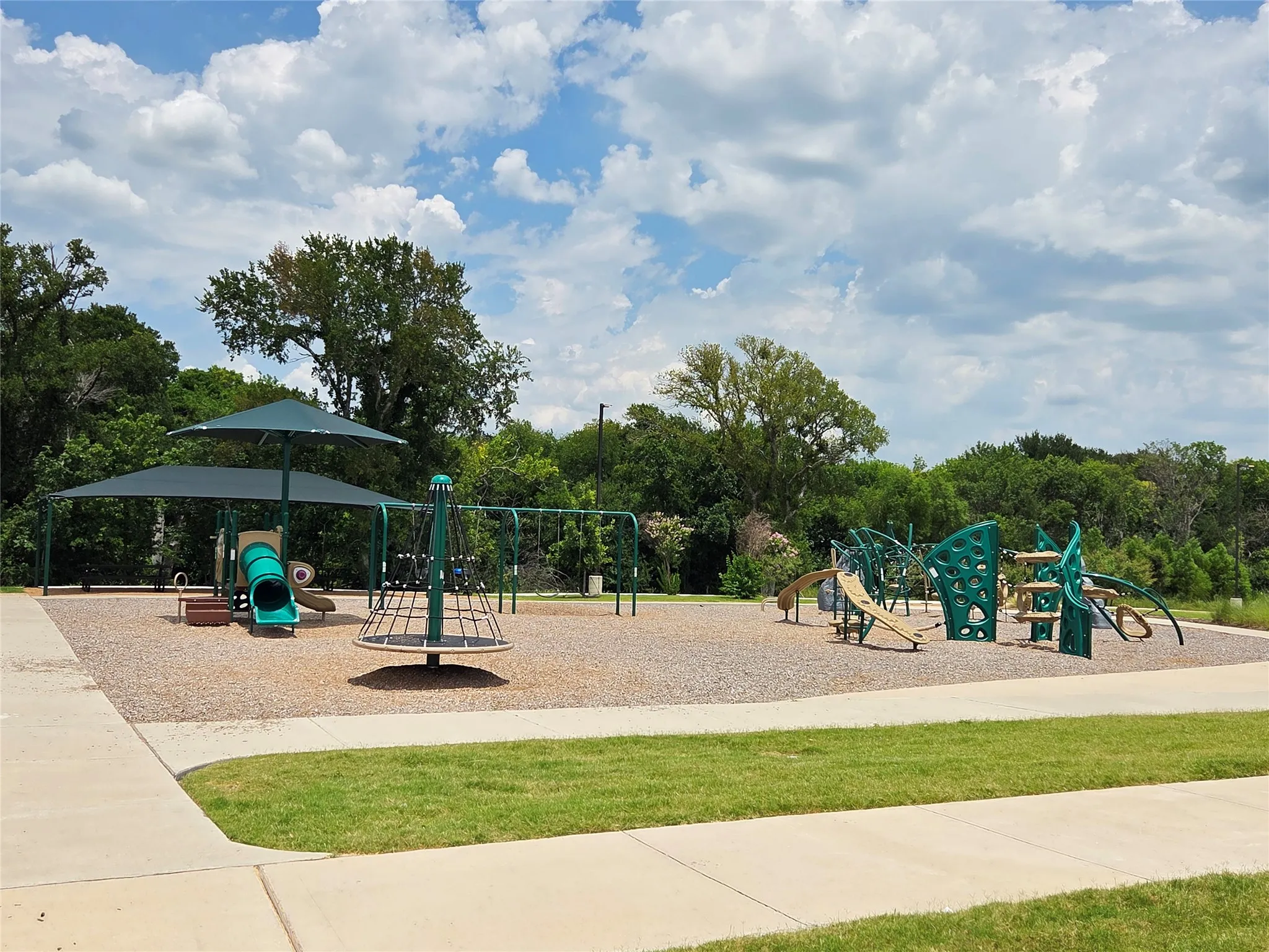 Community playground featuring multiple play structures on a wood chip surface