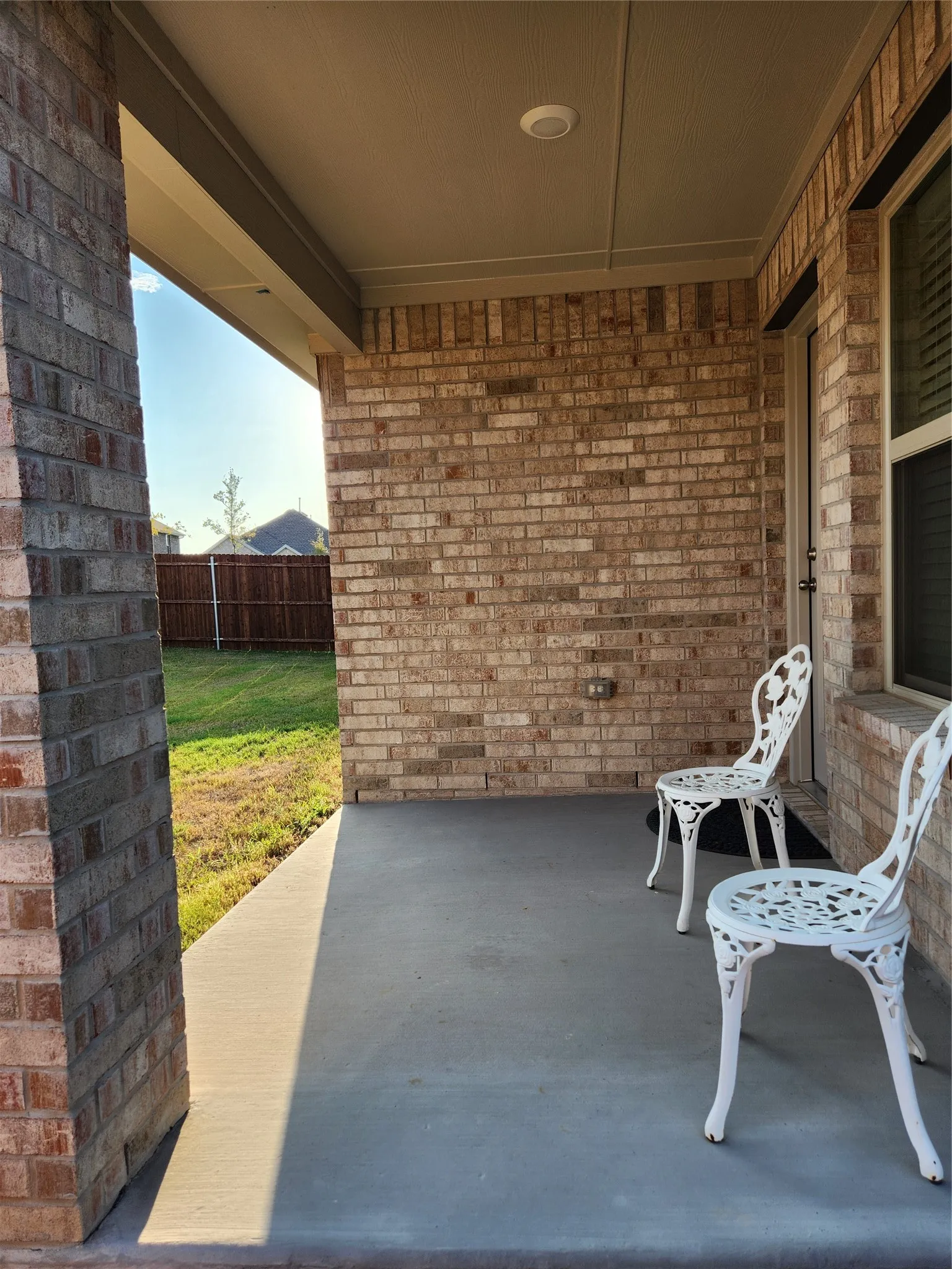 Covered patio with a brick exterior, concrete flooring, and a recessed ceiling light fixture