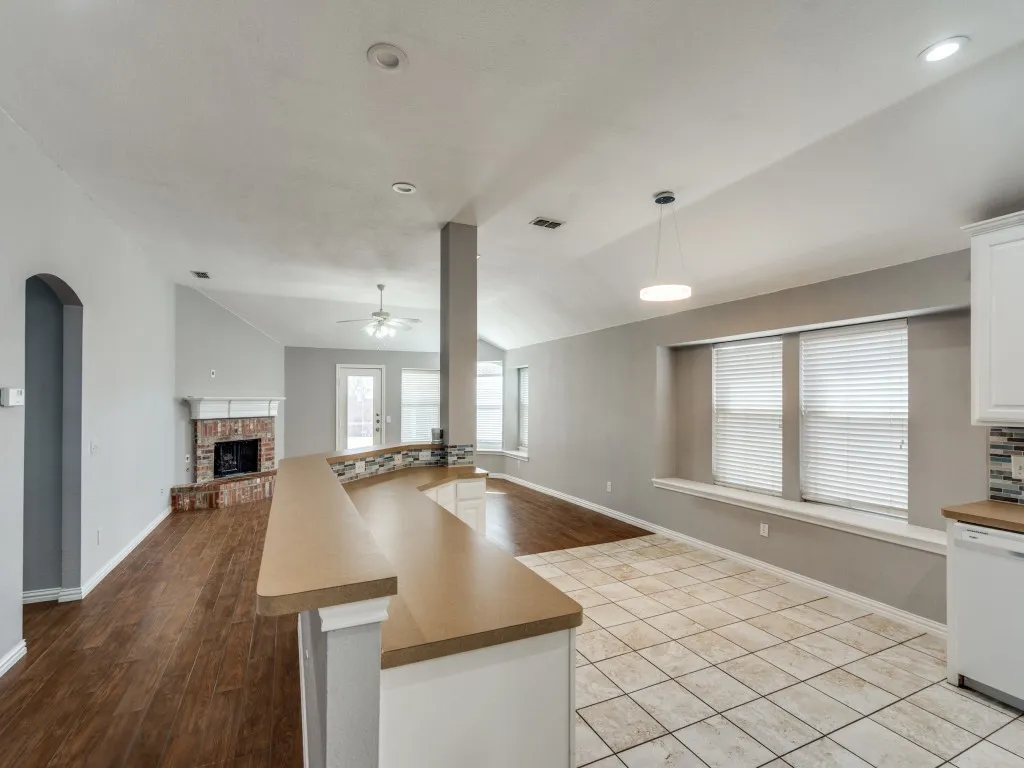 Kitchen with vaulted ceiling, open floor plan, white cabinetry, and white dishwasher