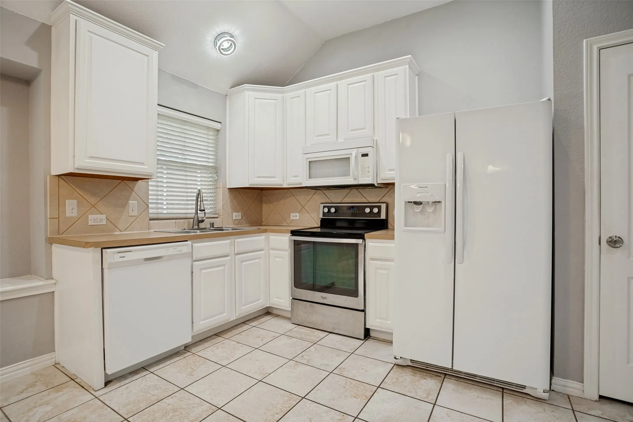 Kitchen featuring white cabinetry, tile backsplash with diamond accents, light-tone countertops, and a stainless steel oven