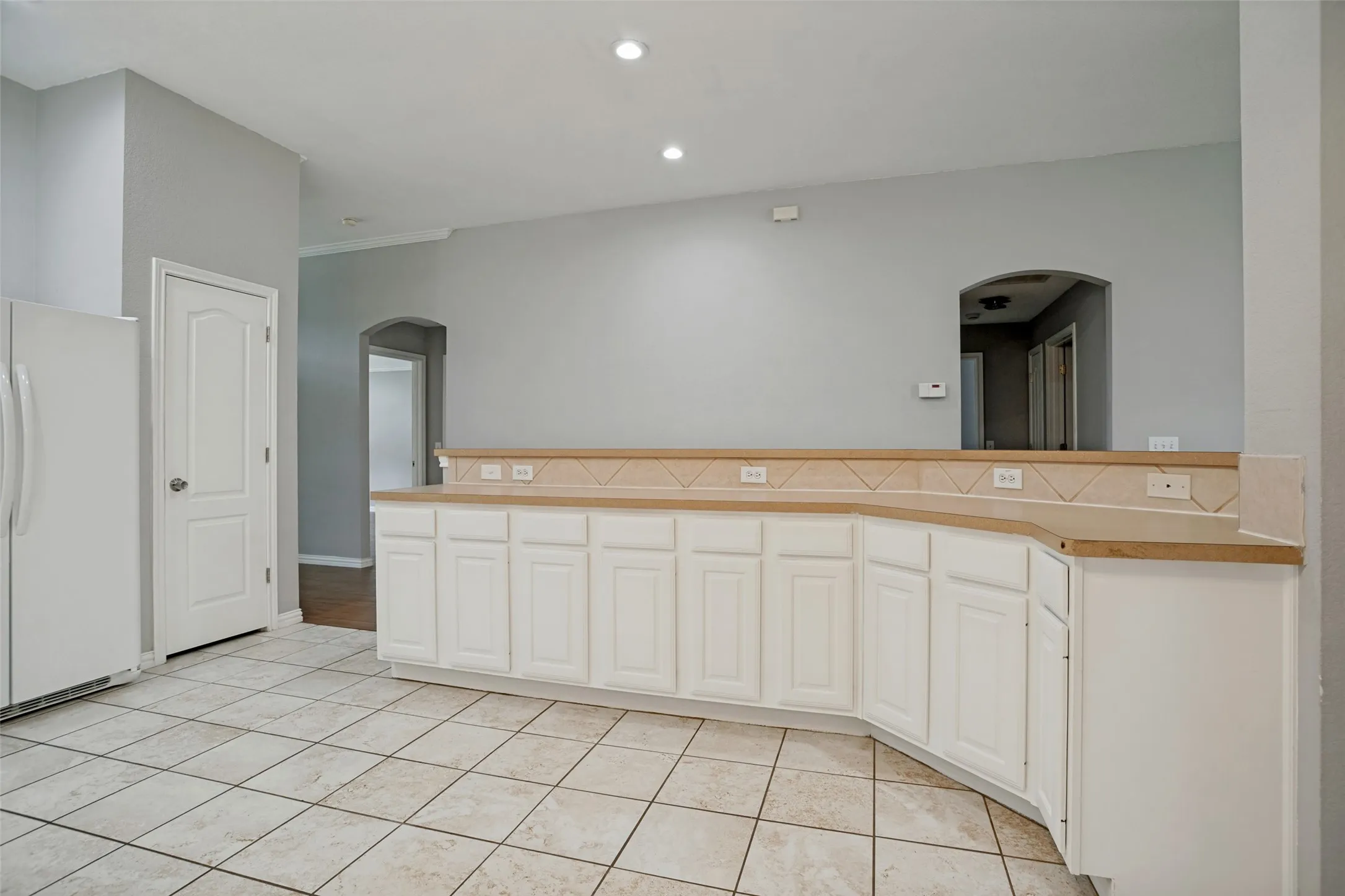 Kitchen featuring white paneled cabinetry, light-toned countertops, and a tile backsplash