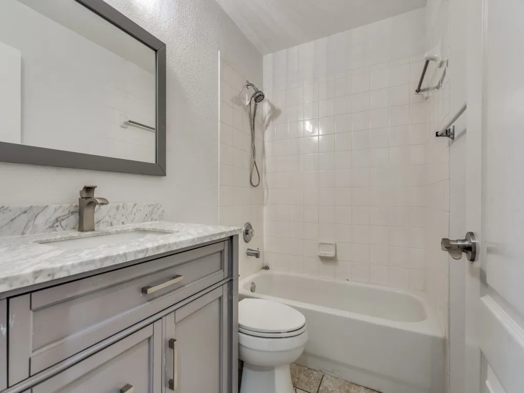 Bathroom featuring toilet, vanity, and  shower combination